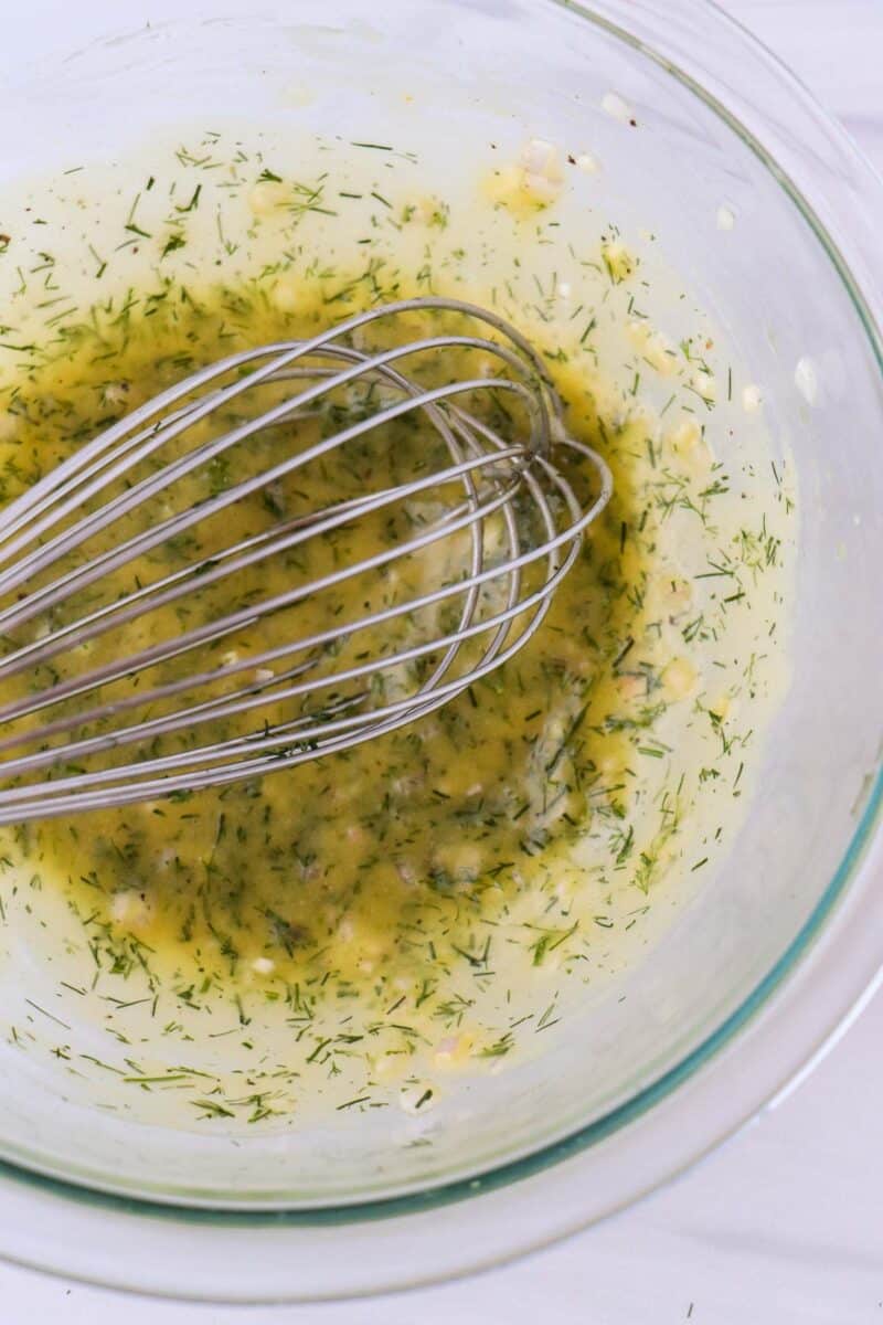 Lemon and Dill Vinaigrette in a glass bowl with a whisk.