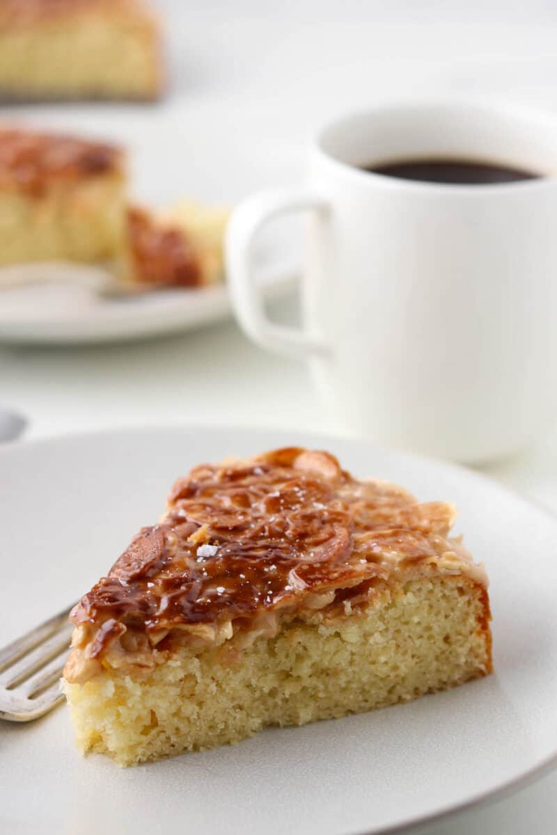 Tosca cake on a plate next to a cup of coffee.