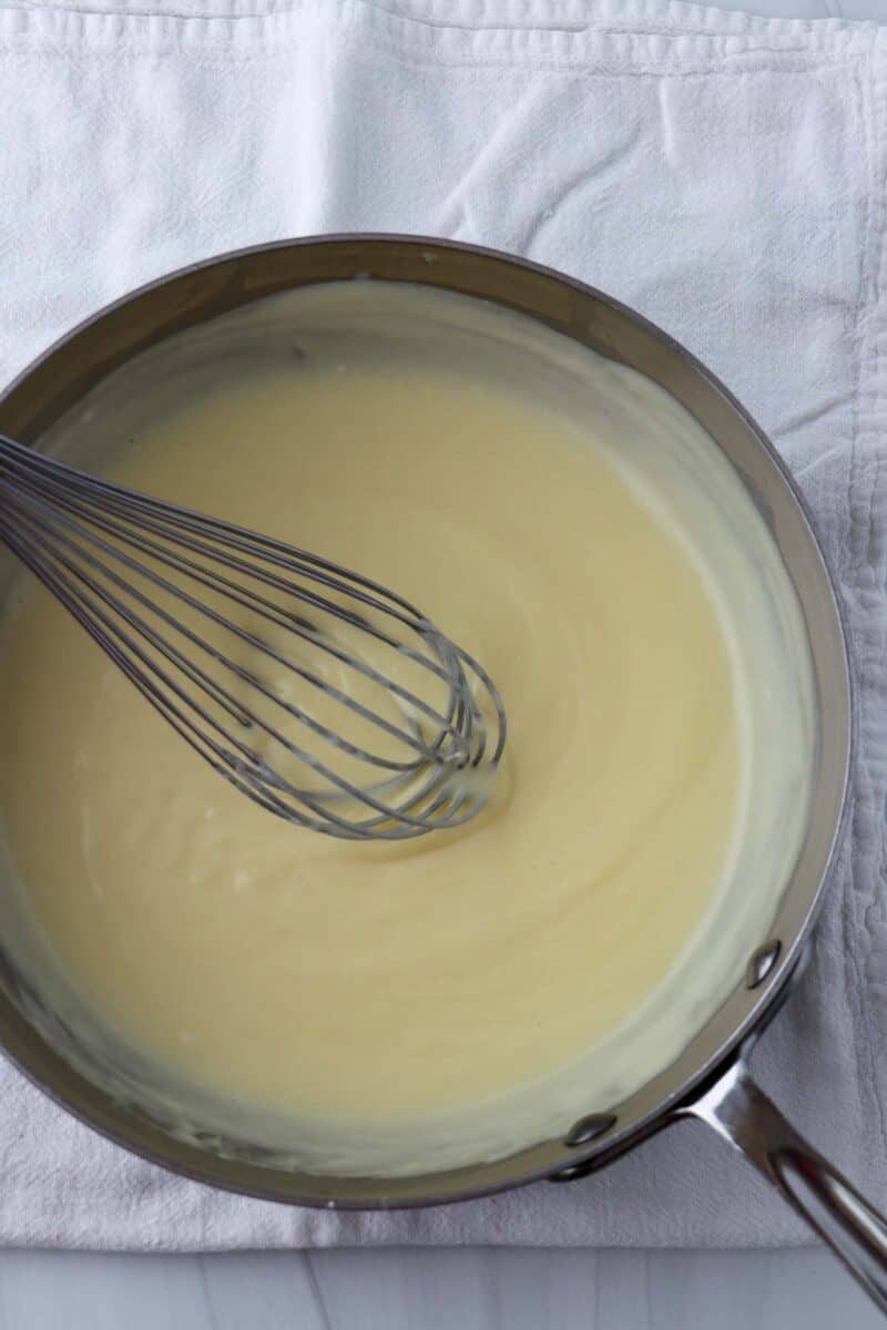 Saucepan with pastry cream and a whisk inside.