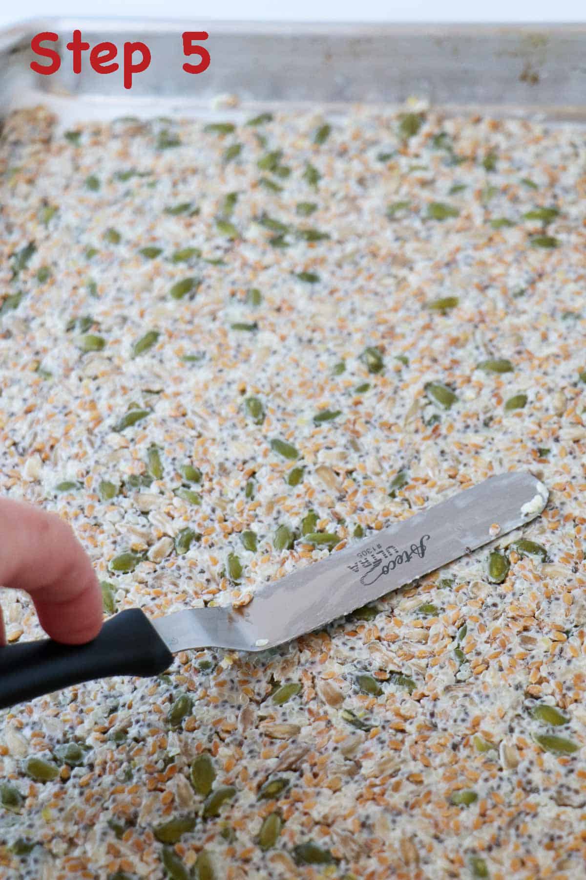 Person spreading seed cracker dough out in a sheet pan.
