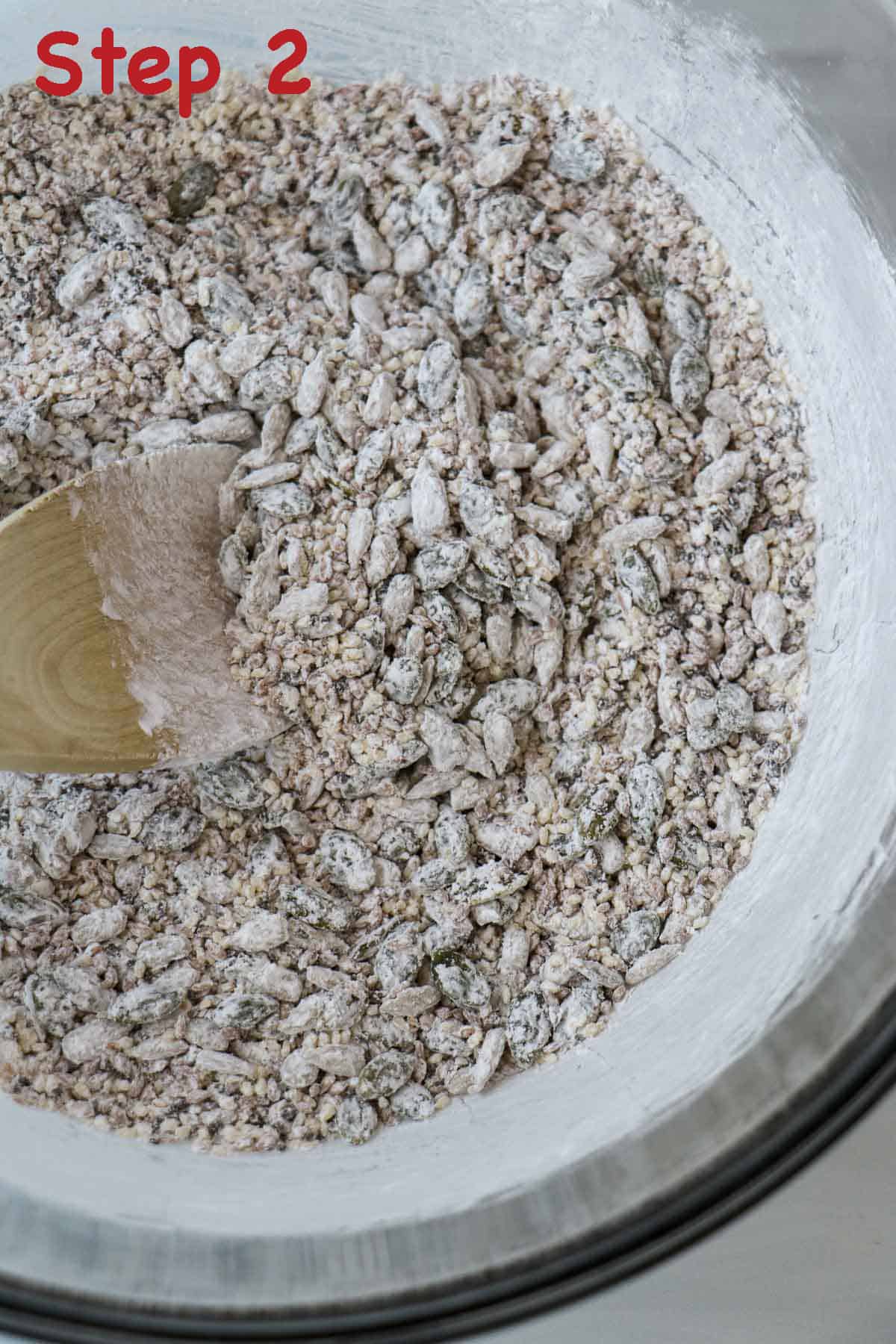 Seed cracker dry ingredients stirred together in a bowl with a wooden spoon.