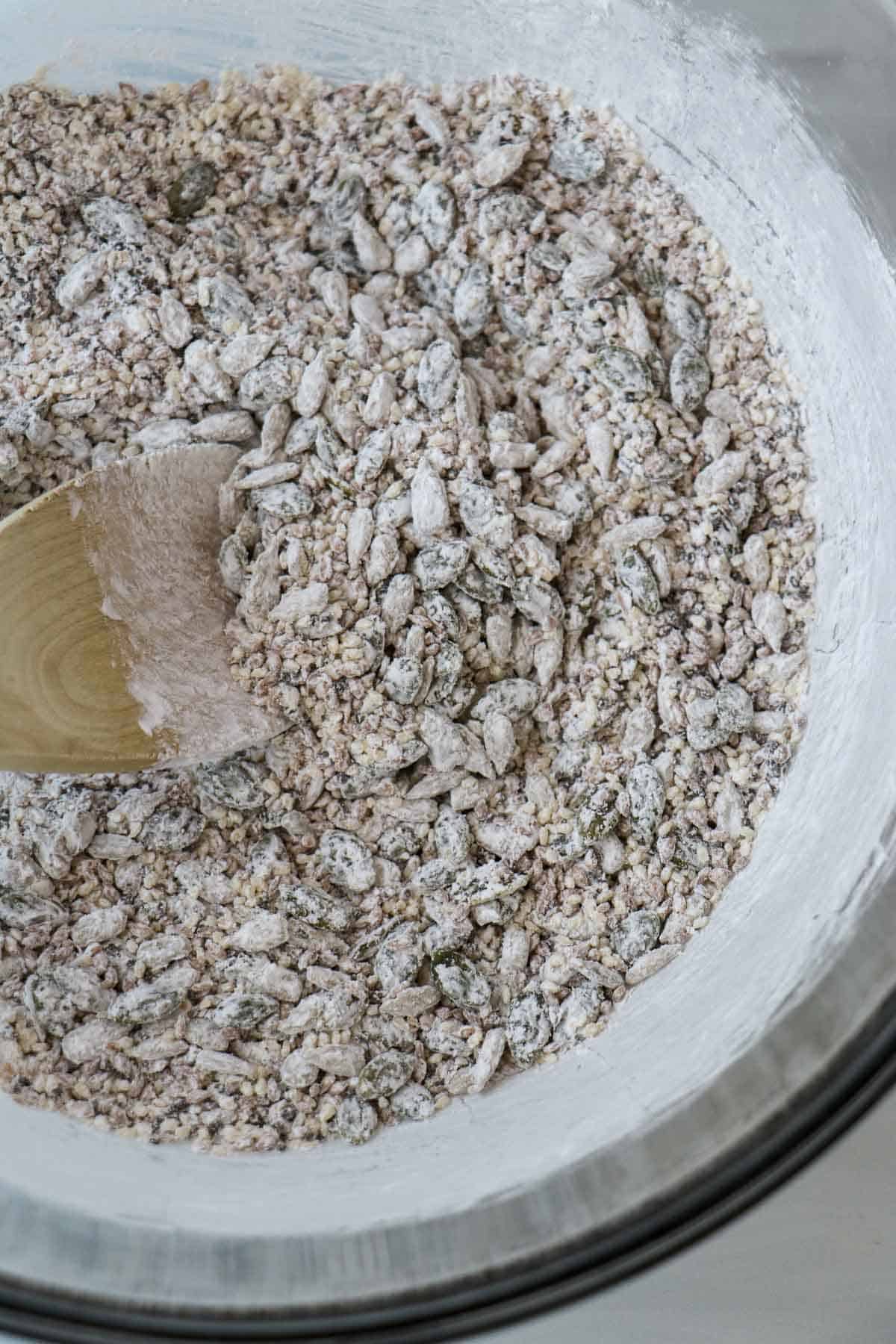 Seeds and cornstarch in a bowl with a wooden spoon.