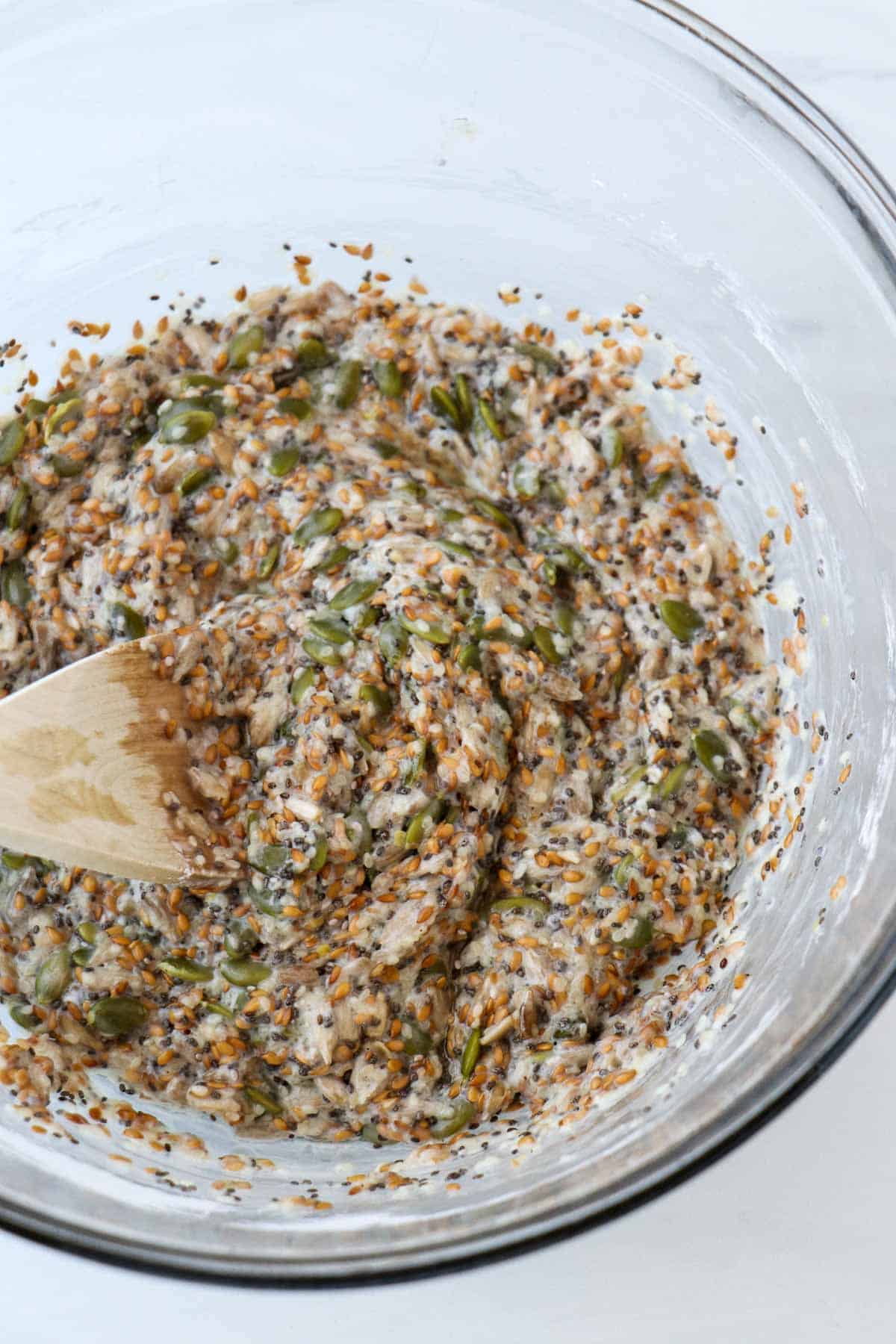 Dough for Norwegian Seed Crispbread in a bowl with a wooden spoon.