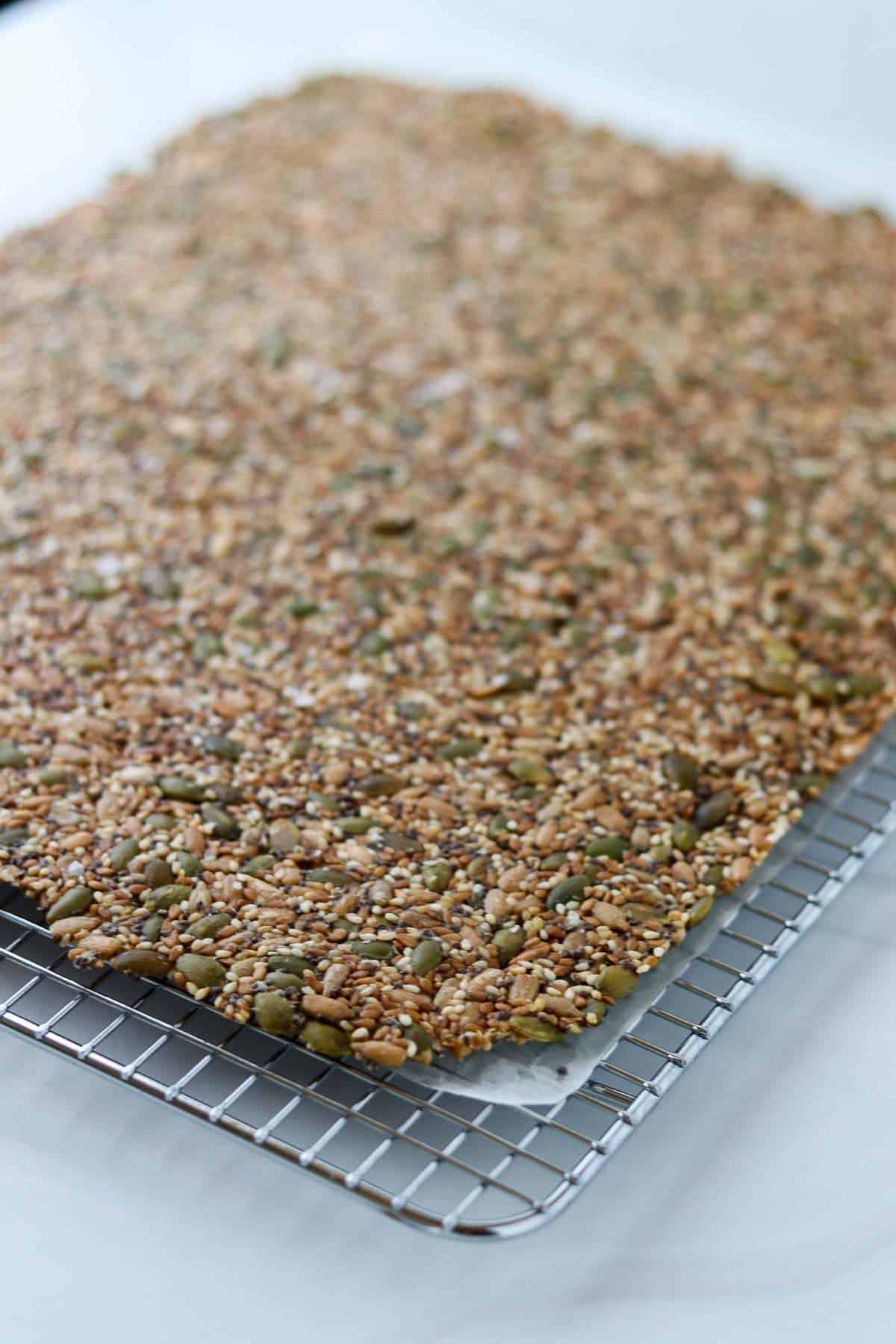 Uncut Norwegian Seed Crispbread on a wire cooling rack.