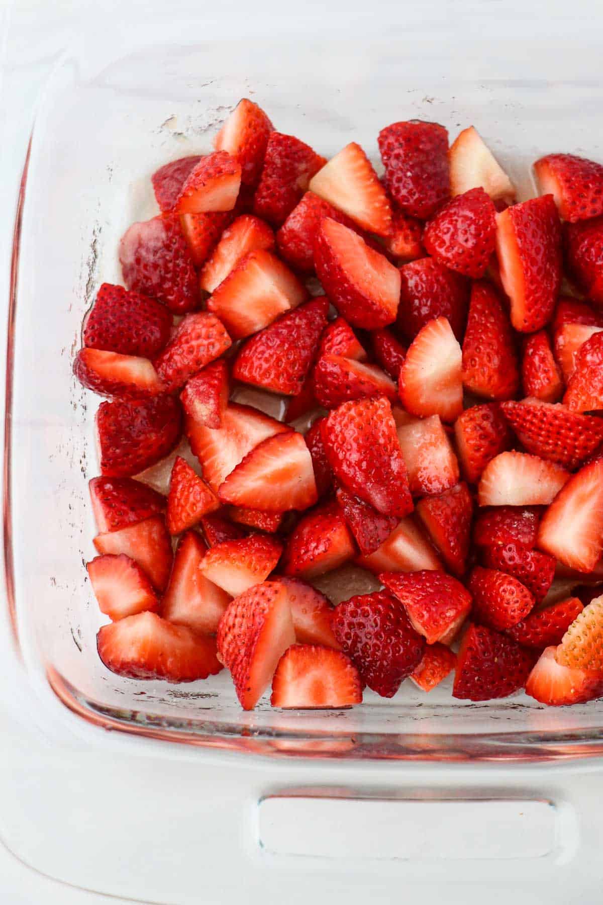 Quartered strawberries in a glass dish.