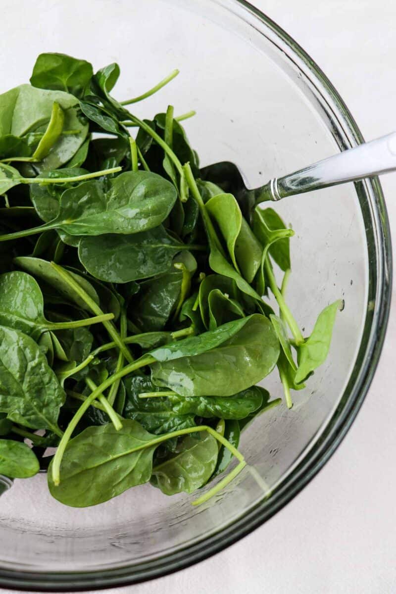 Spinach in a glass bowl with a serving fork.