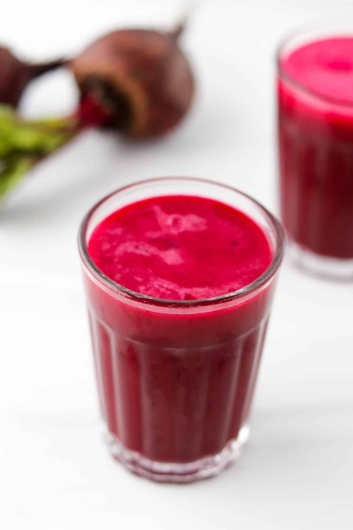 Glass of beet juice next to beets.