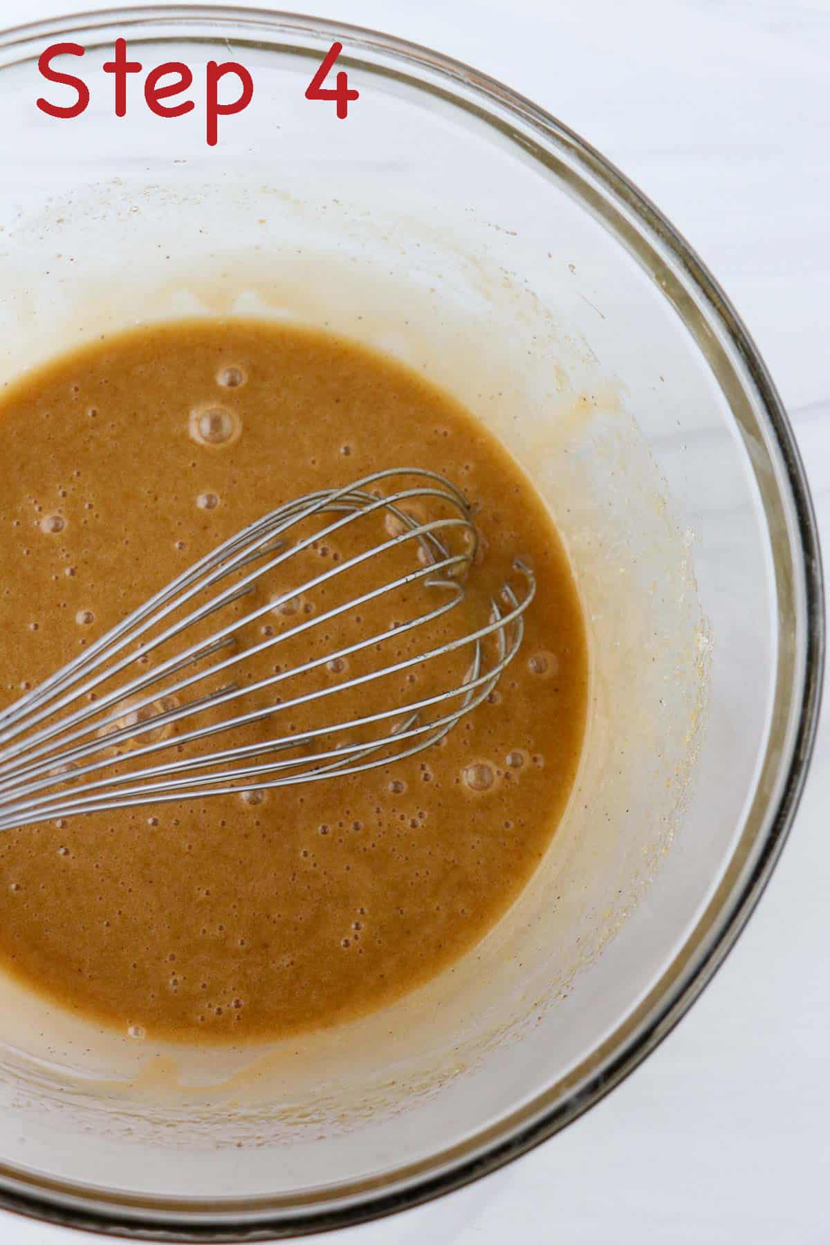Eggs and brown sugar mixed together in a bowl with whisk.