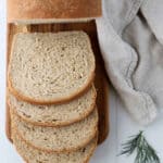 Soft Dill Bread on a cutting board next to a towel and a sprig of dill.