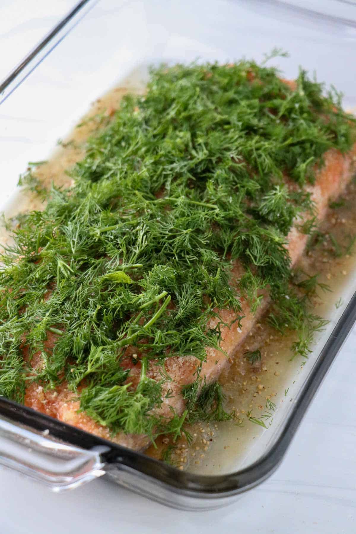 Salmon in a glass dish covered with chopped dill.