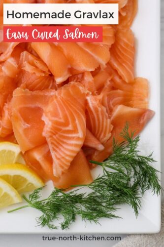 Pinterest pin of cured salmon on a plate with dill and lemon wedges.