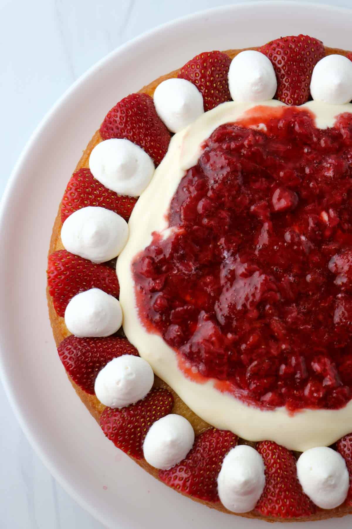 Cake topped with strawberries, whipped cream, pastry cream and roasted strawberries.