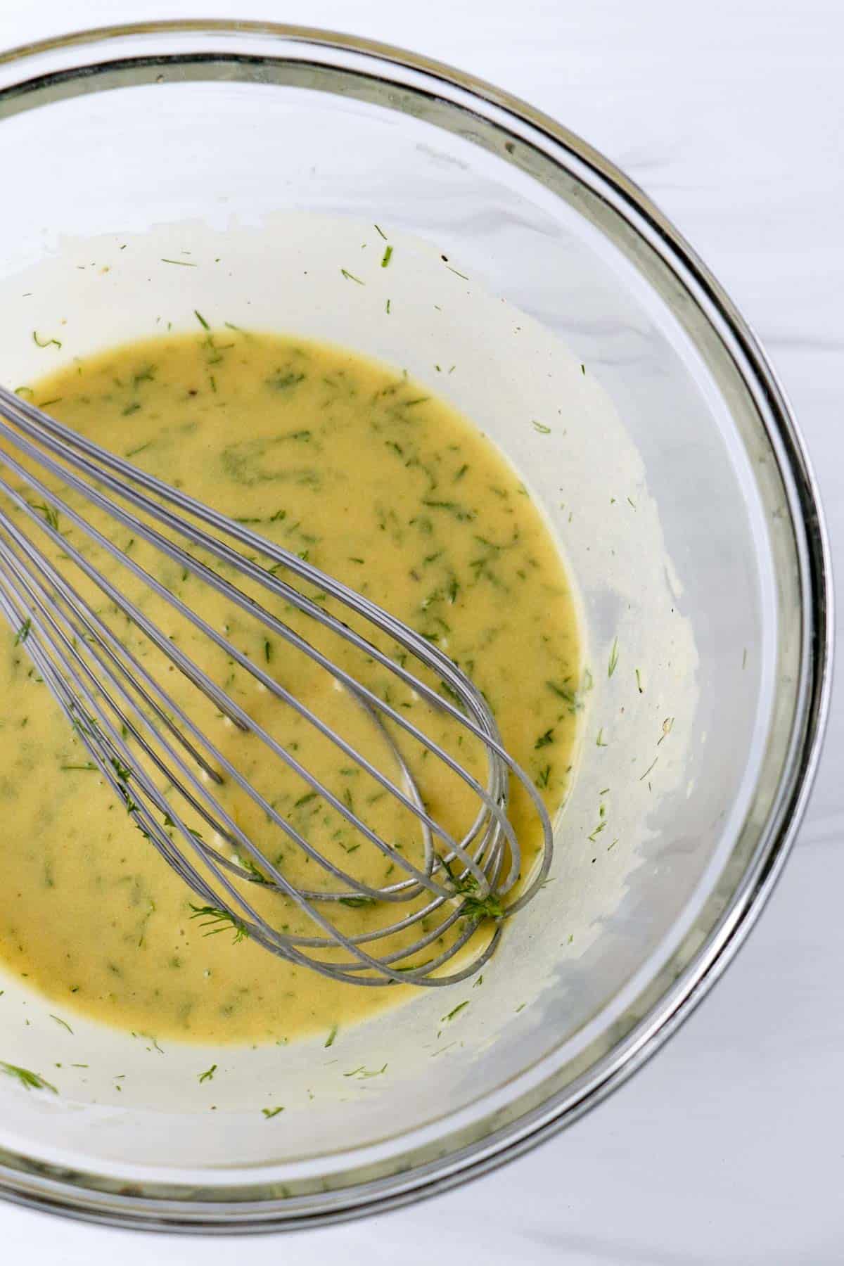 Mustard Dill Sauce for Gravlax in a glass bowl with a whisk.