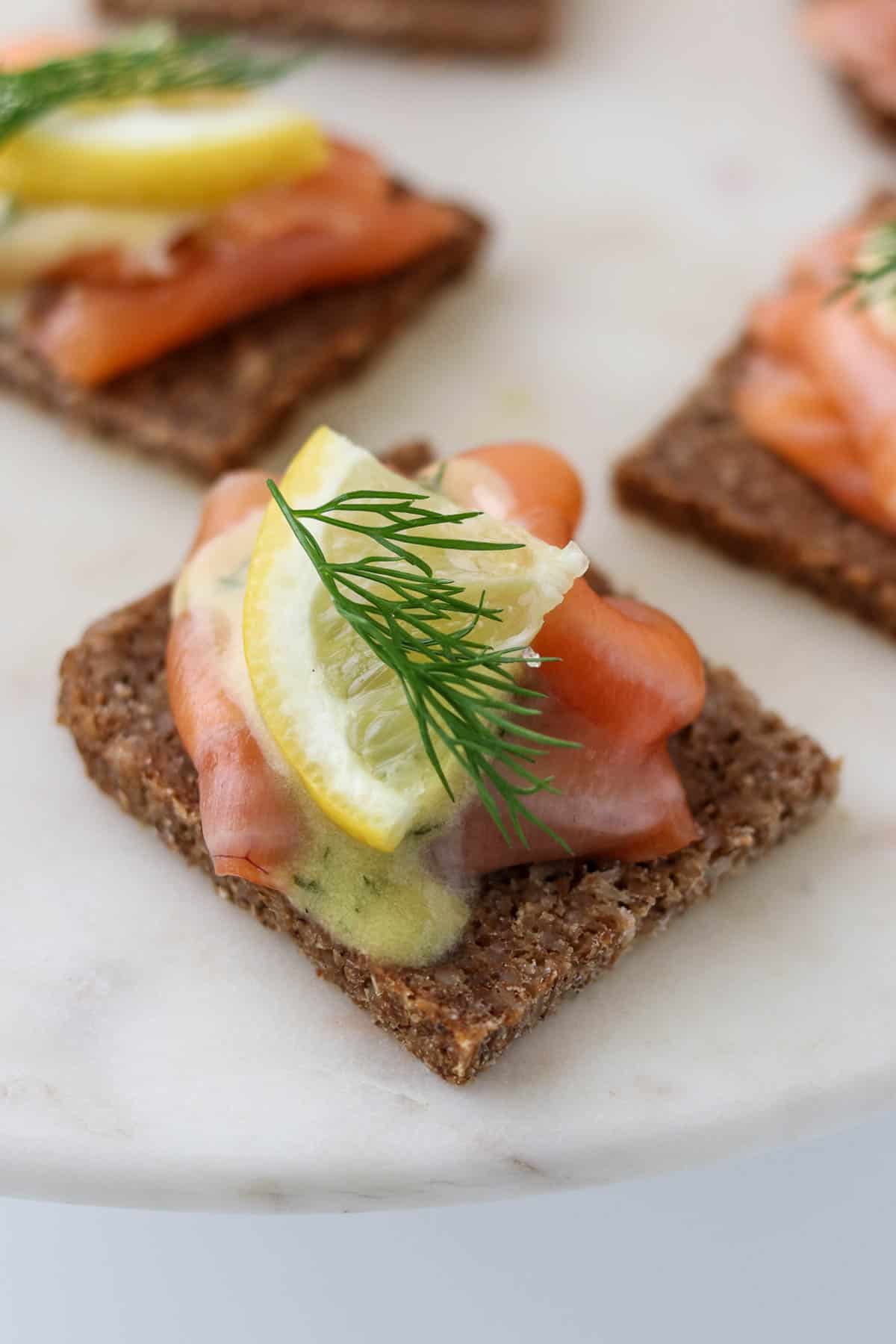 Gravlax on rye bread topped with mustard sauce, lemon and dill.