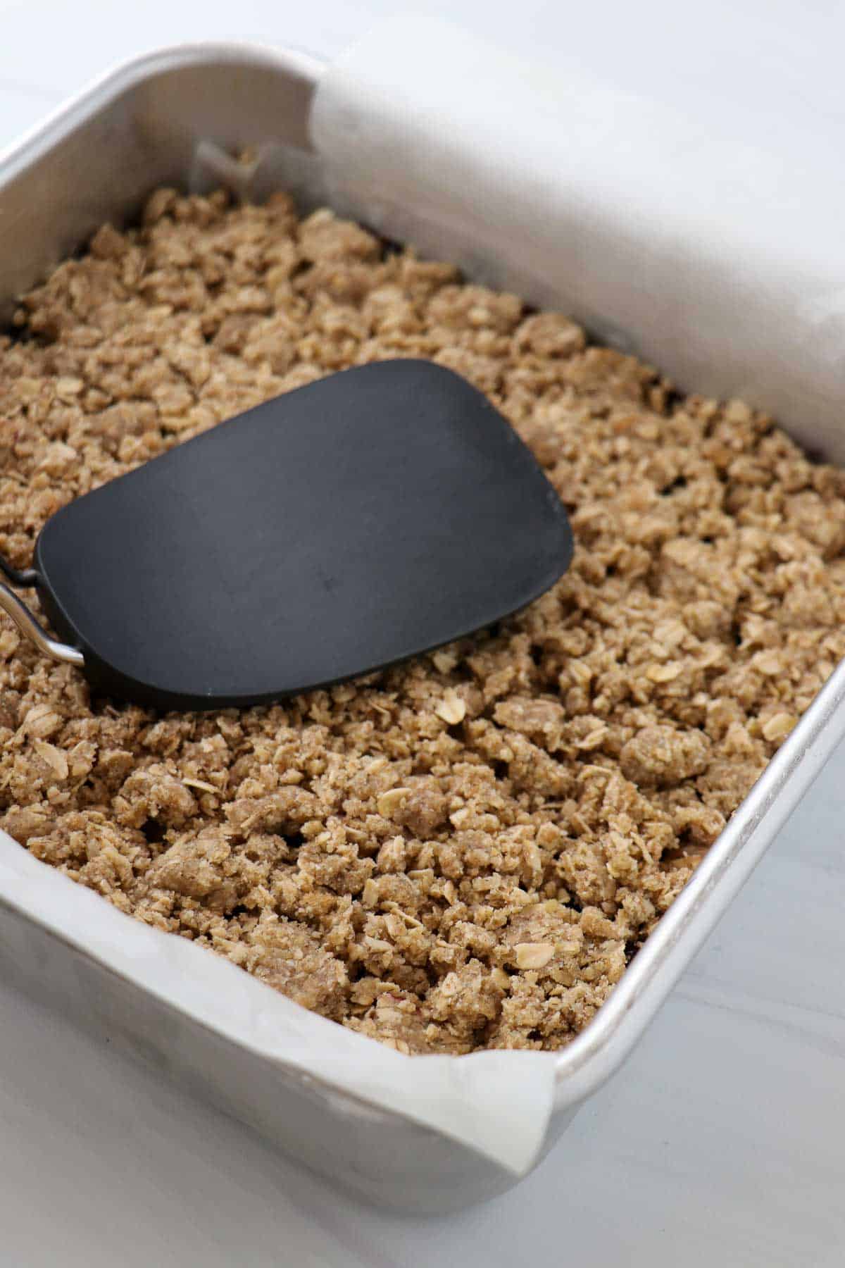 Unbaked Lemon Blueberry Crumble Bars in a metal pan with a spatula.
