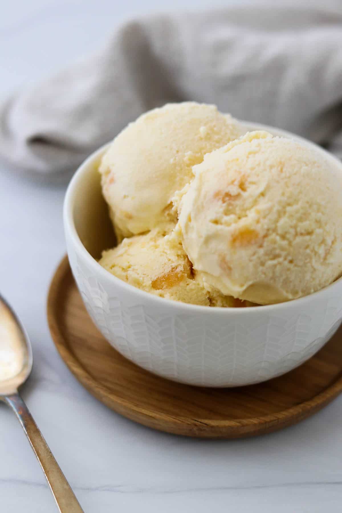 Peaches and Cream Ice Cream in a small bowl next to a spoon.