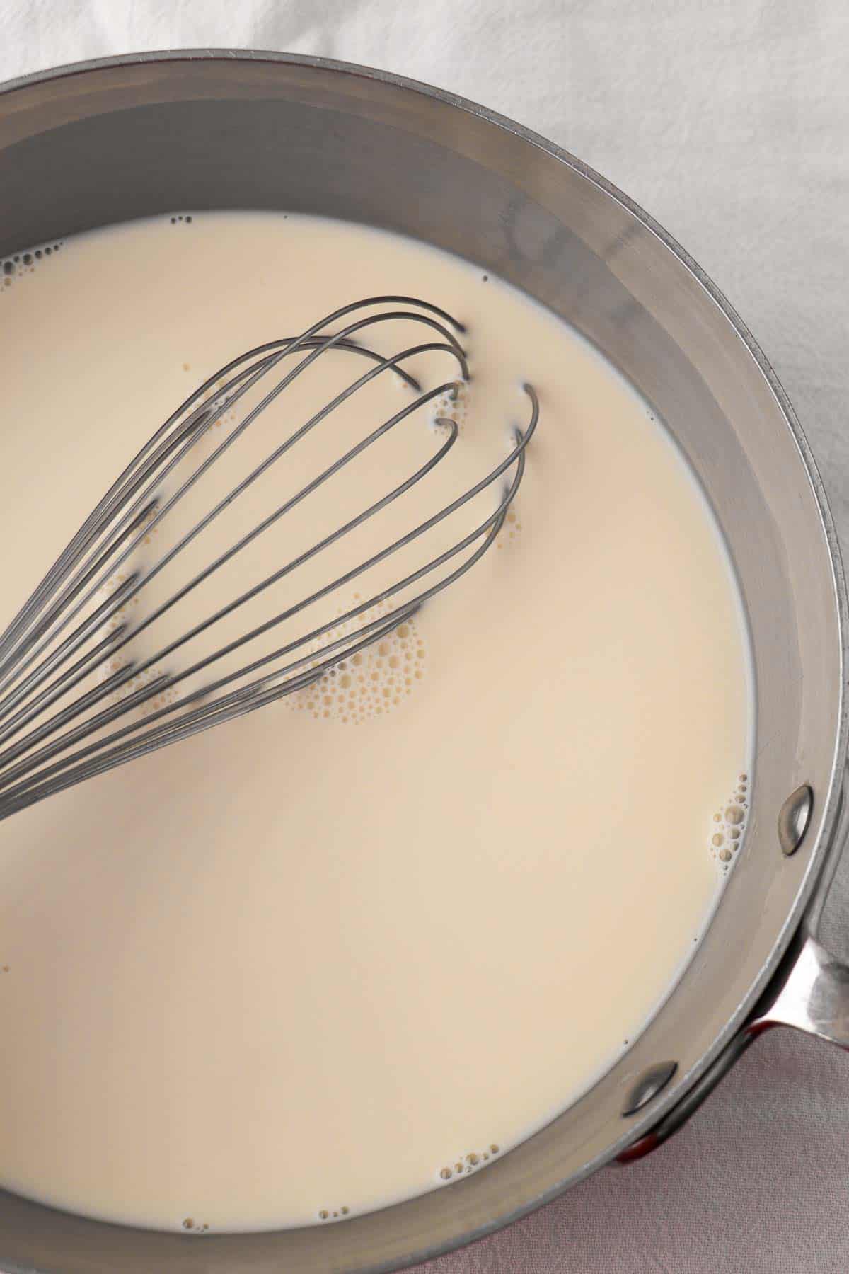 Cream in a saucepan with a whisk.