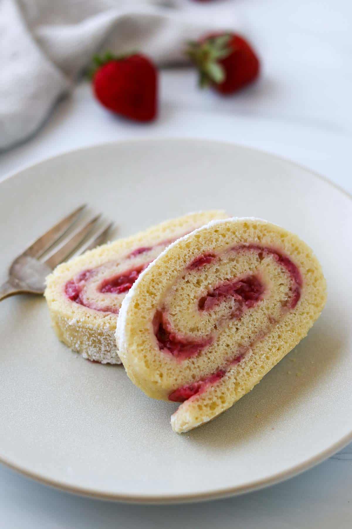 Strawberry Roll Cake on a white plate next to a fork.