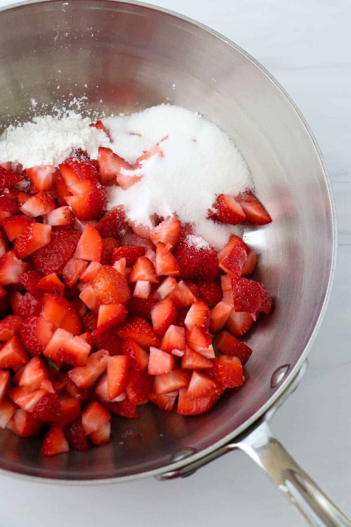 Cut up strawberries, sugar and cornstarch in a saucepan.