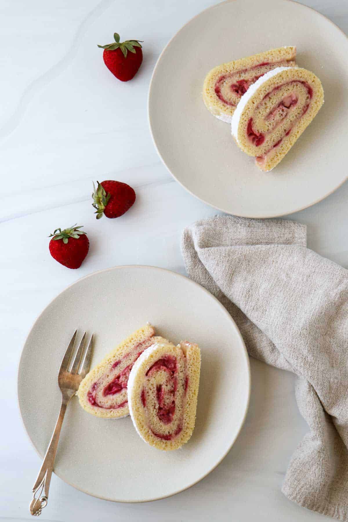 Overhead view of two plates of Strawberry Roll Cake slices.