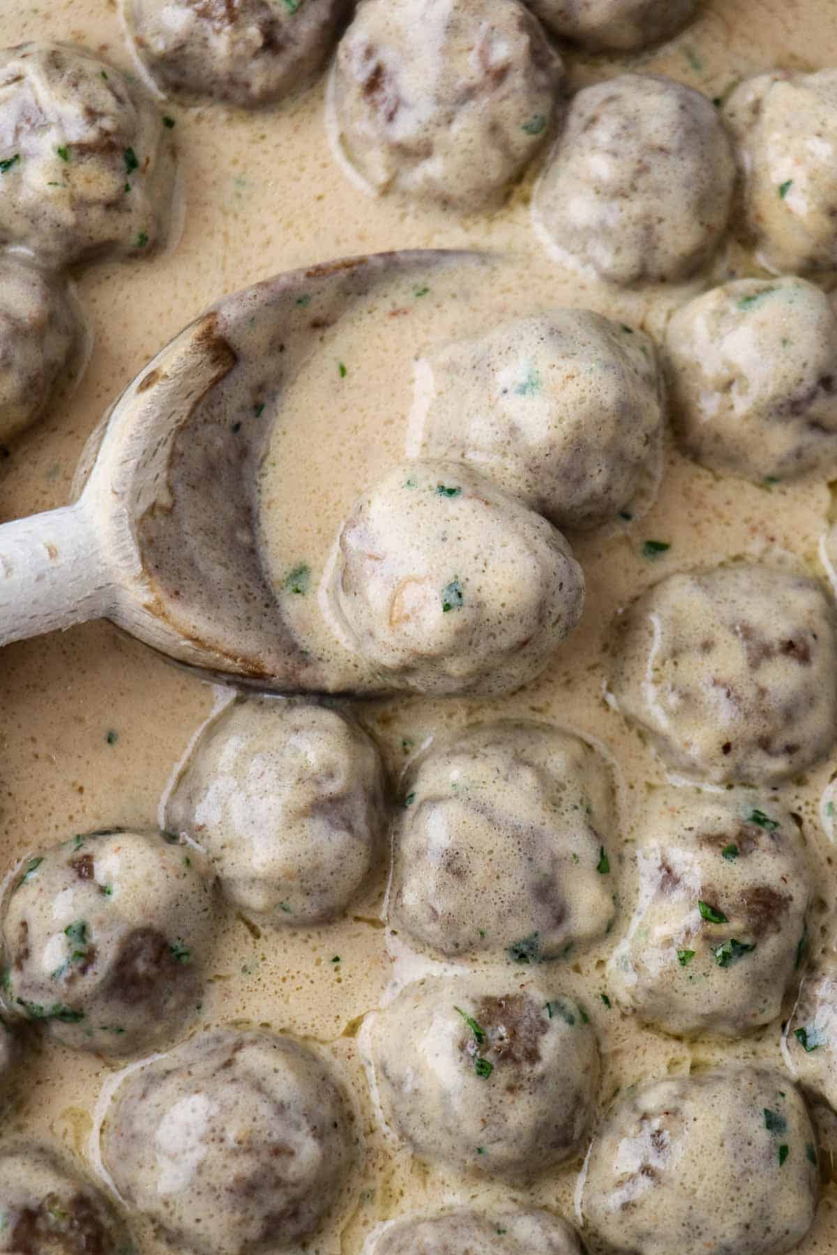 Close up of Swedish Meatballs with Gravy and a wooden spoon.