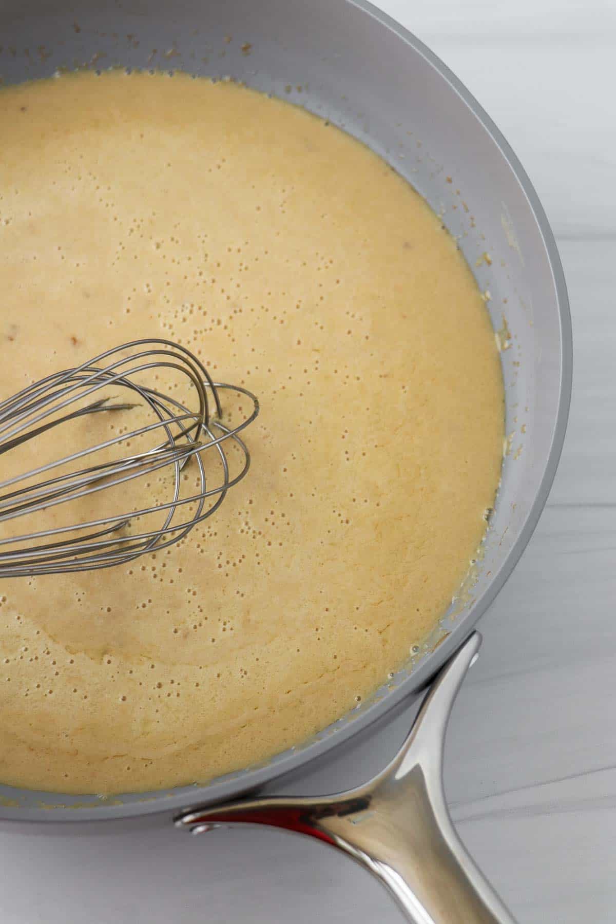 Gravy in a gray pan with a whisk.