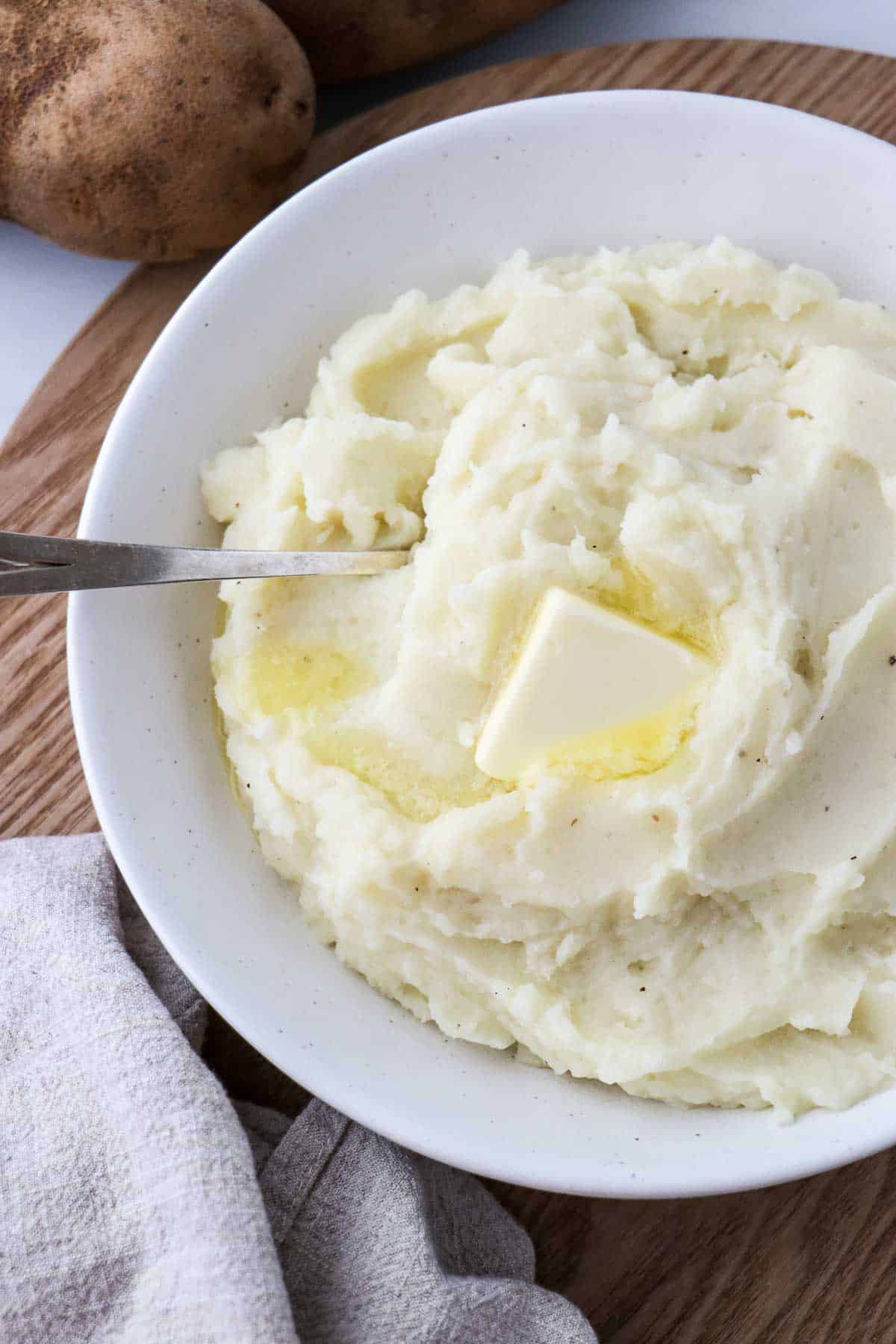 Overhead shot of mashed potatoes in a bowl with butter and a spoon.