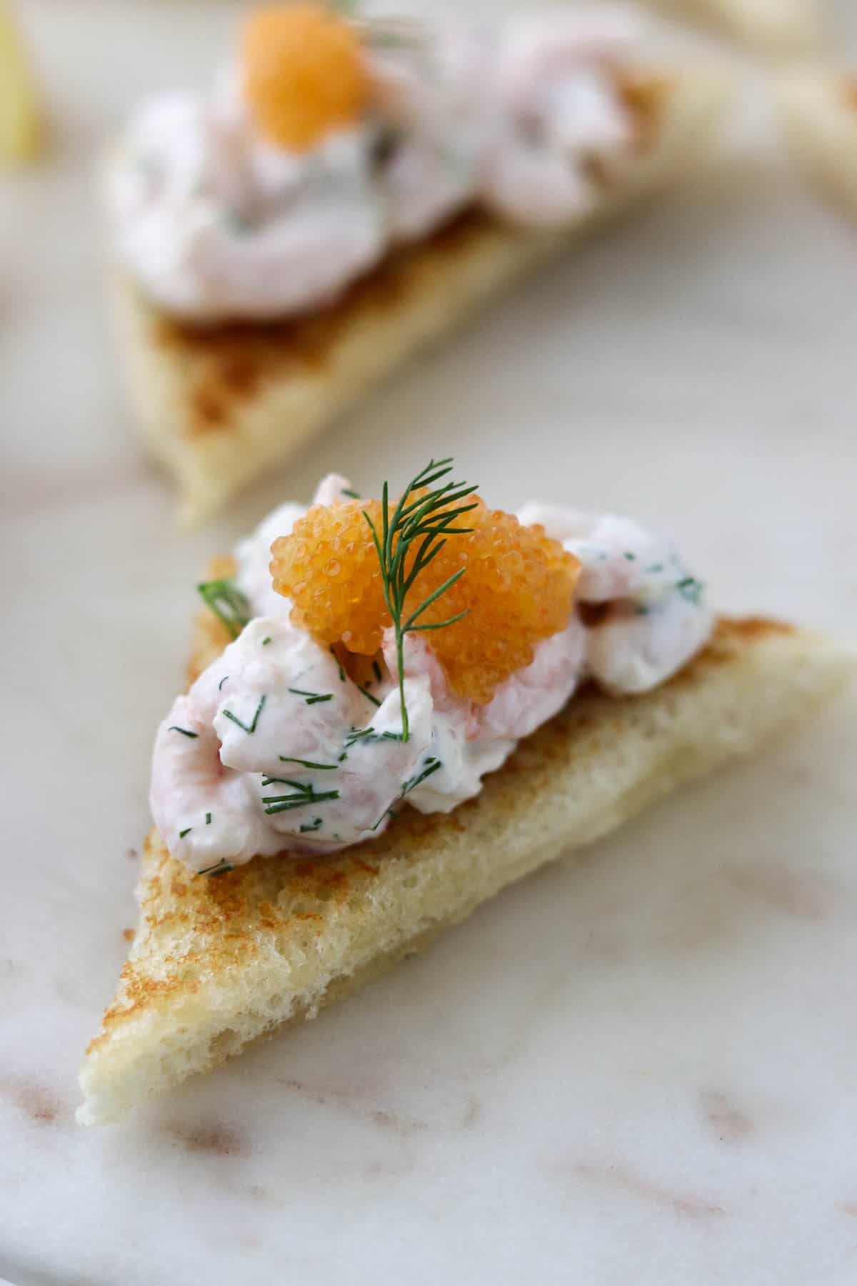 Close up of Toast Skagen topped with caviar and a sprig of dill.