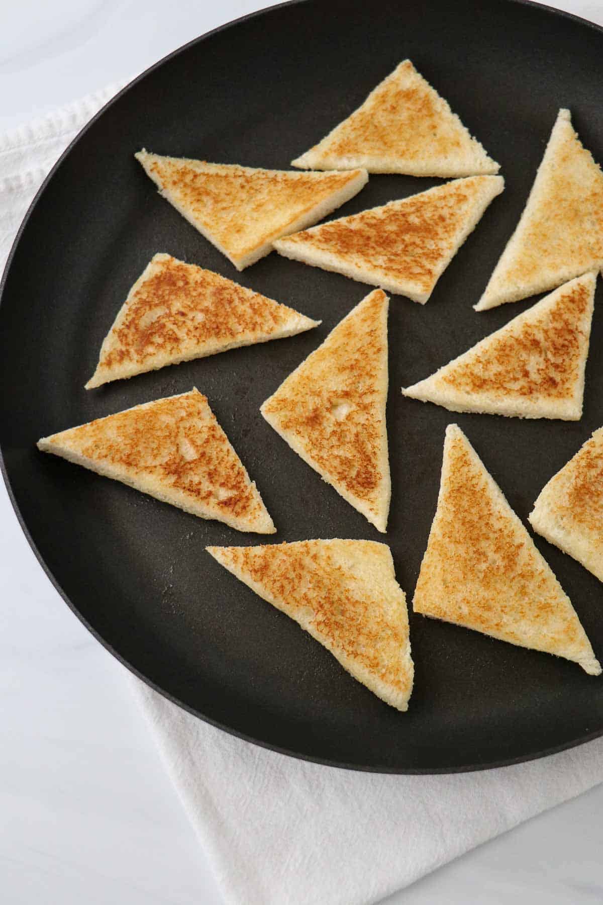 Crispy white bread triangles in a nonstick skillet.