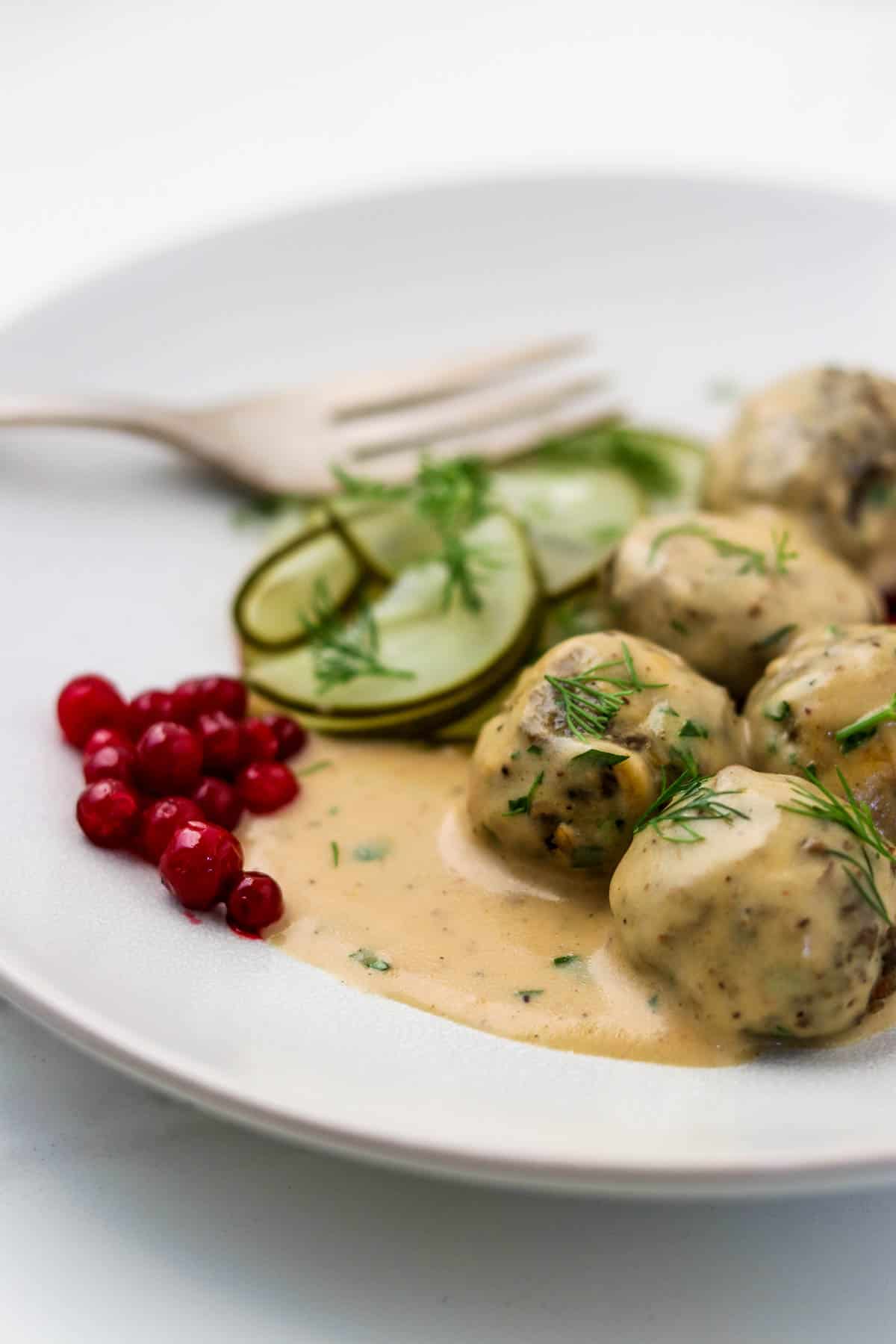 Vegetarian Swedish Meatballs on a plate with lingonberries and cucumbers.