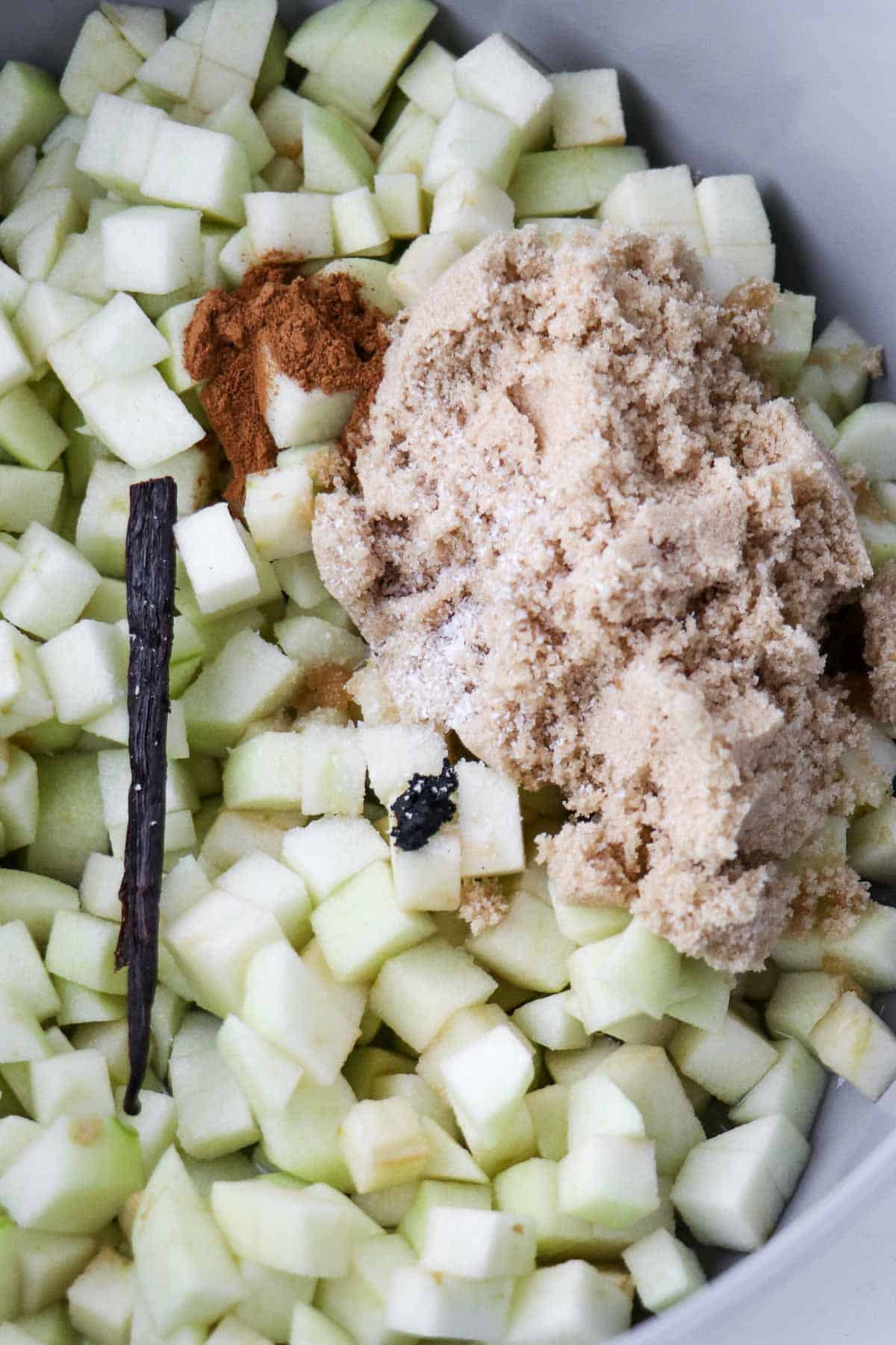 Chopped up apples, a vanilla bean, cinnamon and brown sugar in a saucepan.