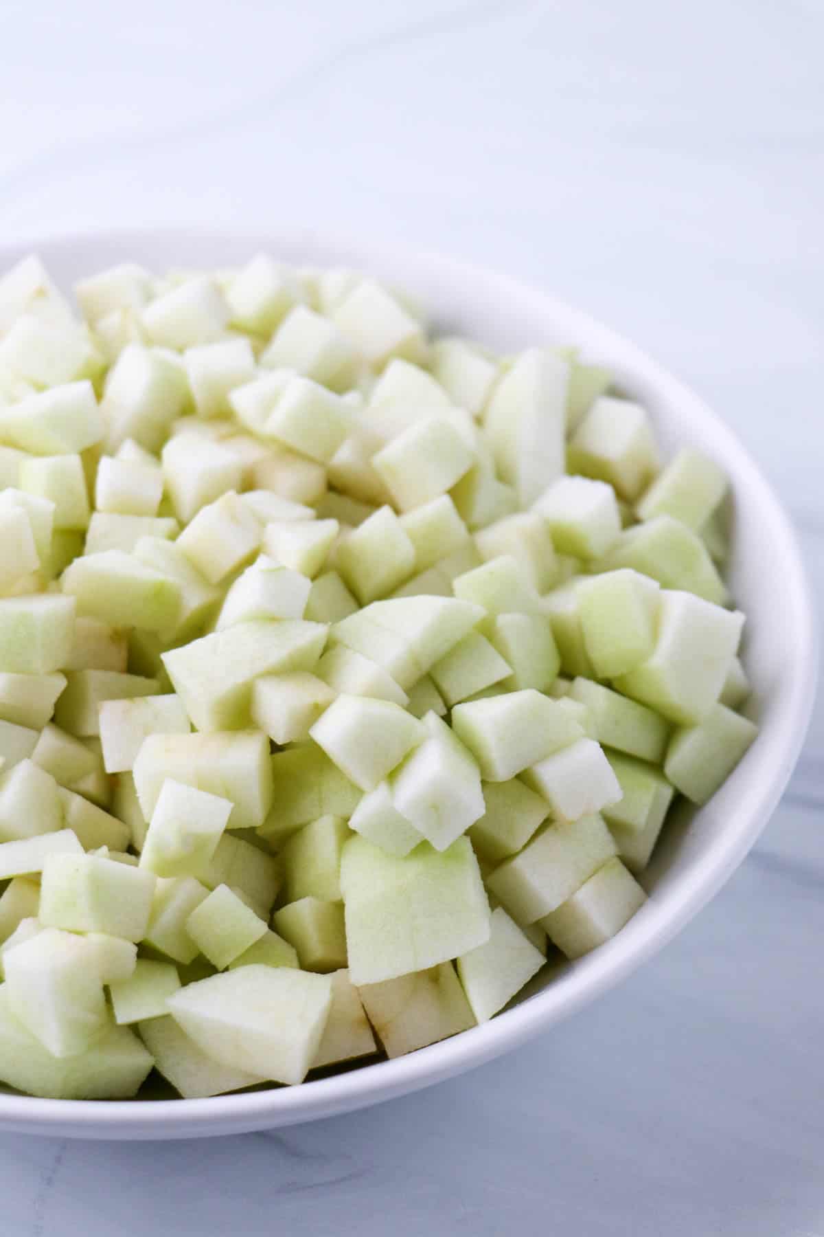 Chopped up apples in a white bowl.