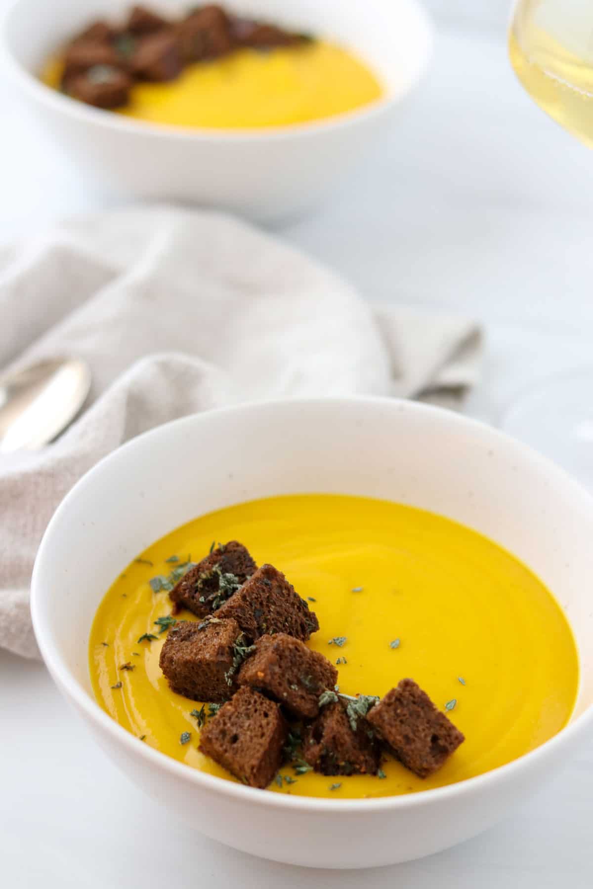 Two bowls of butternut squash soup topped with rye croutons.