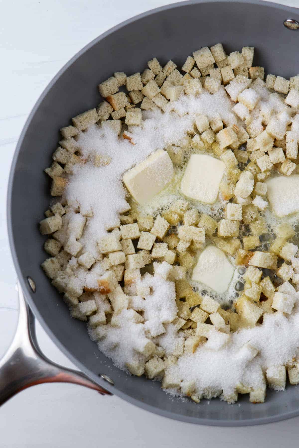 Bread cubes, sugar and butter in a pan.