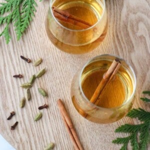Cup of white mulled wine with cinnamon sticks and spices.
