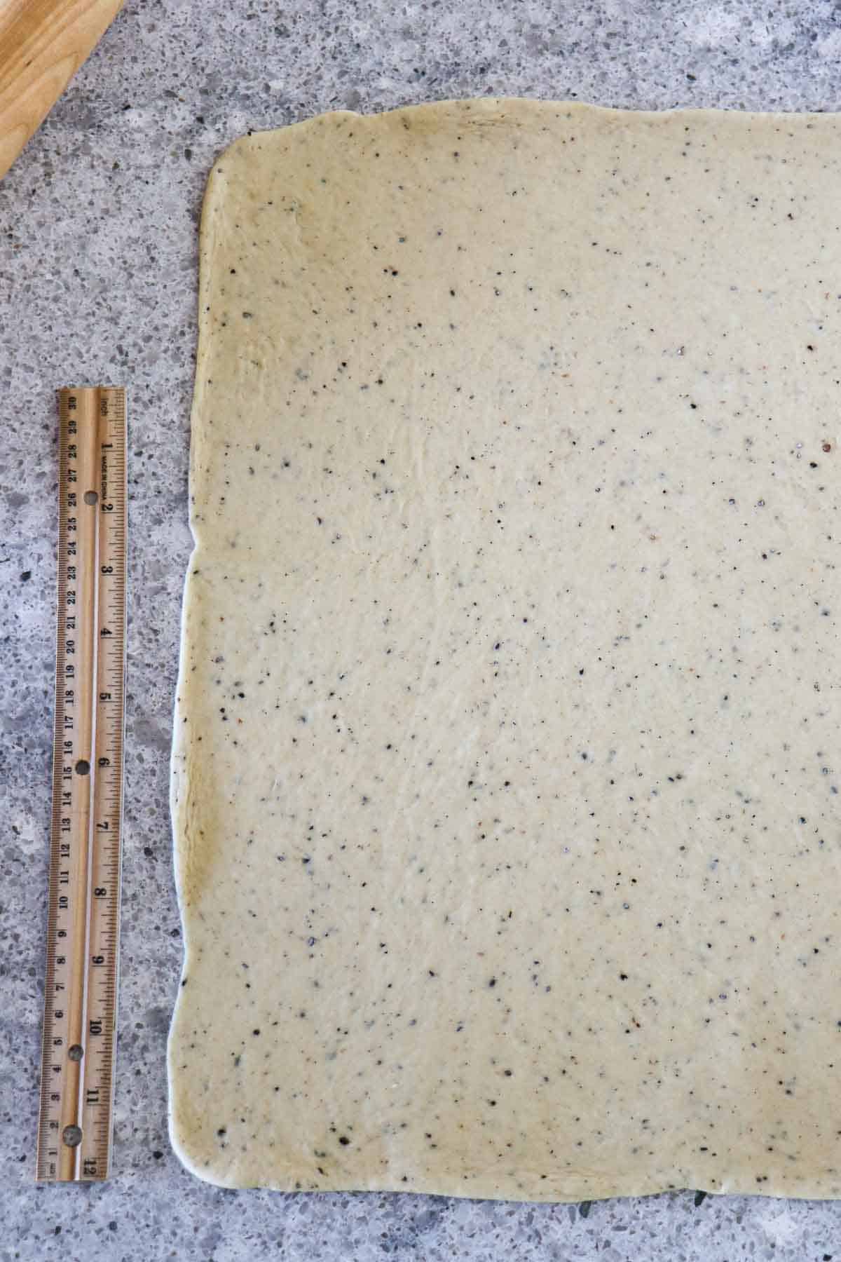 Rolled out cardamom dough on a counter next to a ruler.