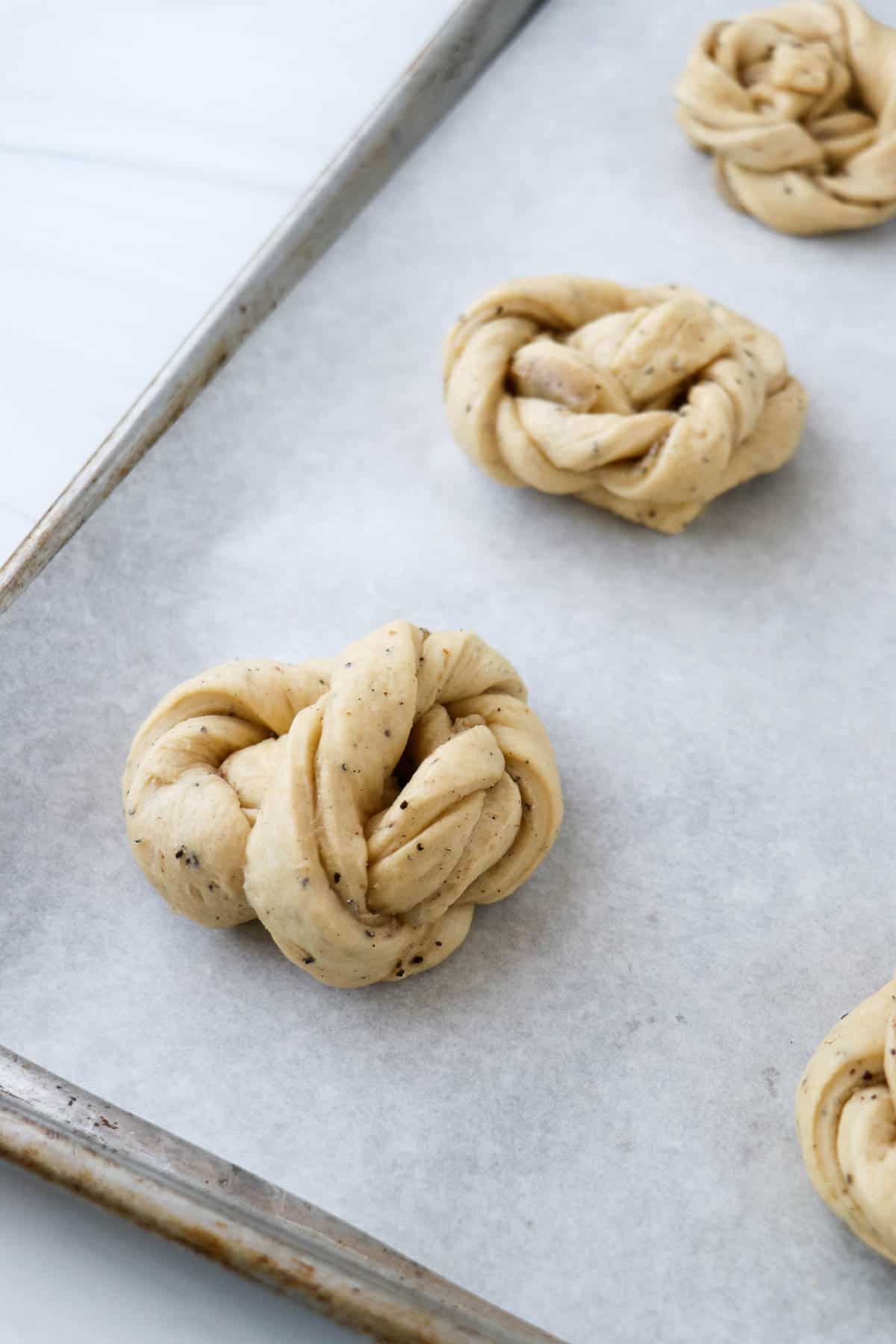 Unbaked cardamom buns on a baking sheet.