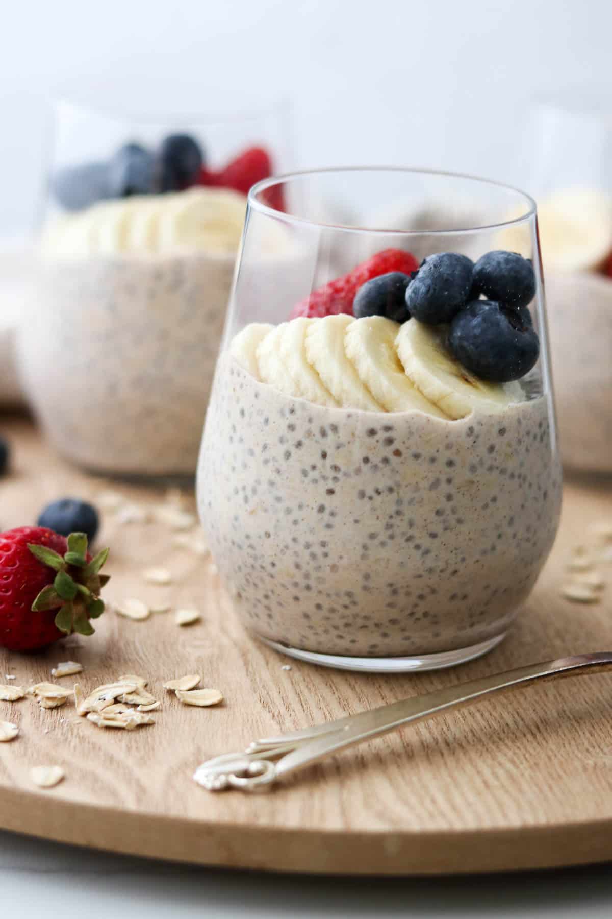 Glasses of overnight oats topped with bananas, blueberries and strawberries.