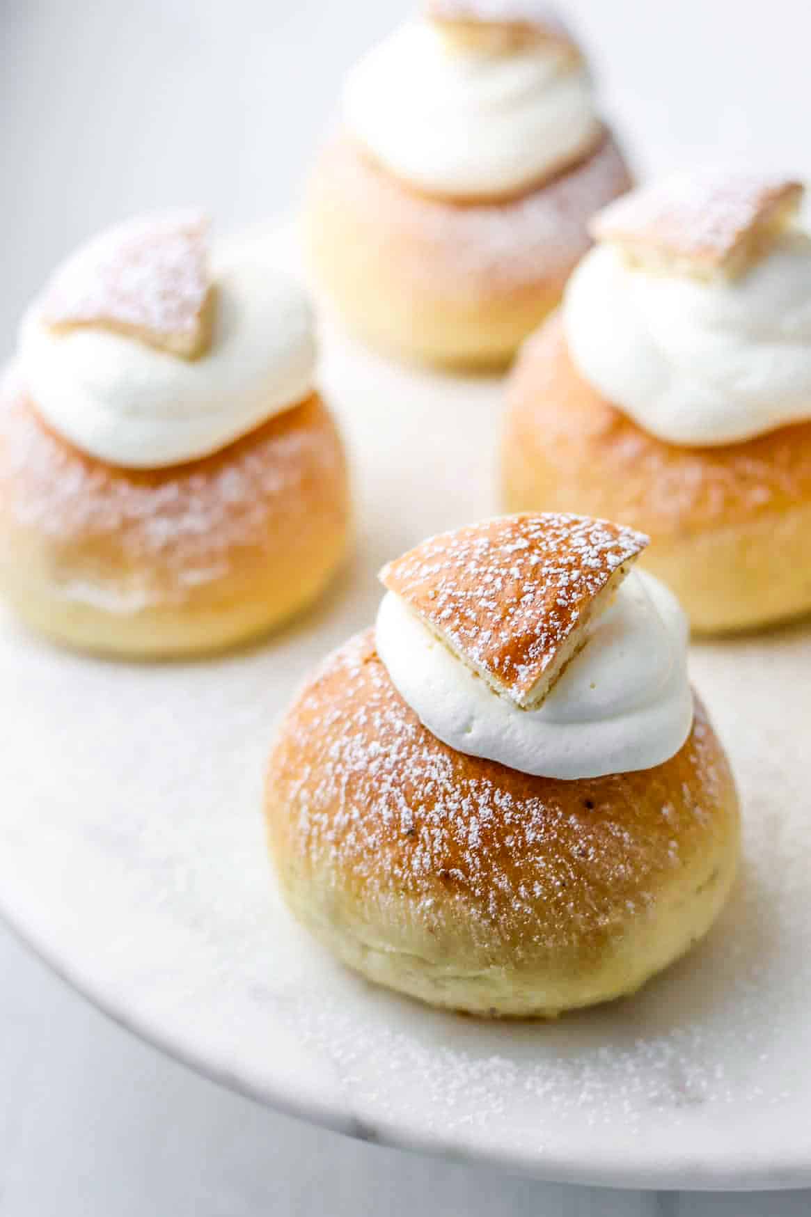 Four Swedish semlor on a marble plate.