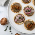 Crackers topped with Vegetarian Mushroom Pâtë and pickled shallots and mustard seeds.