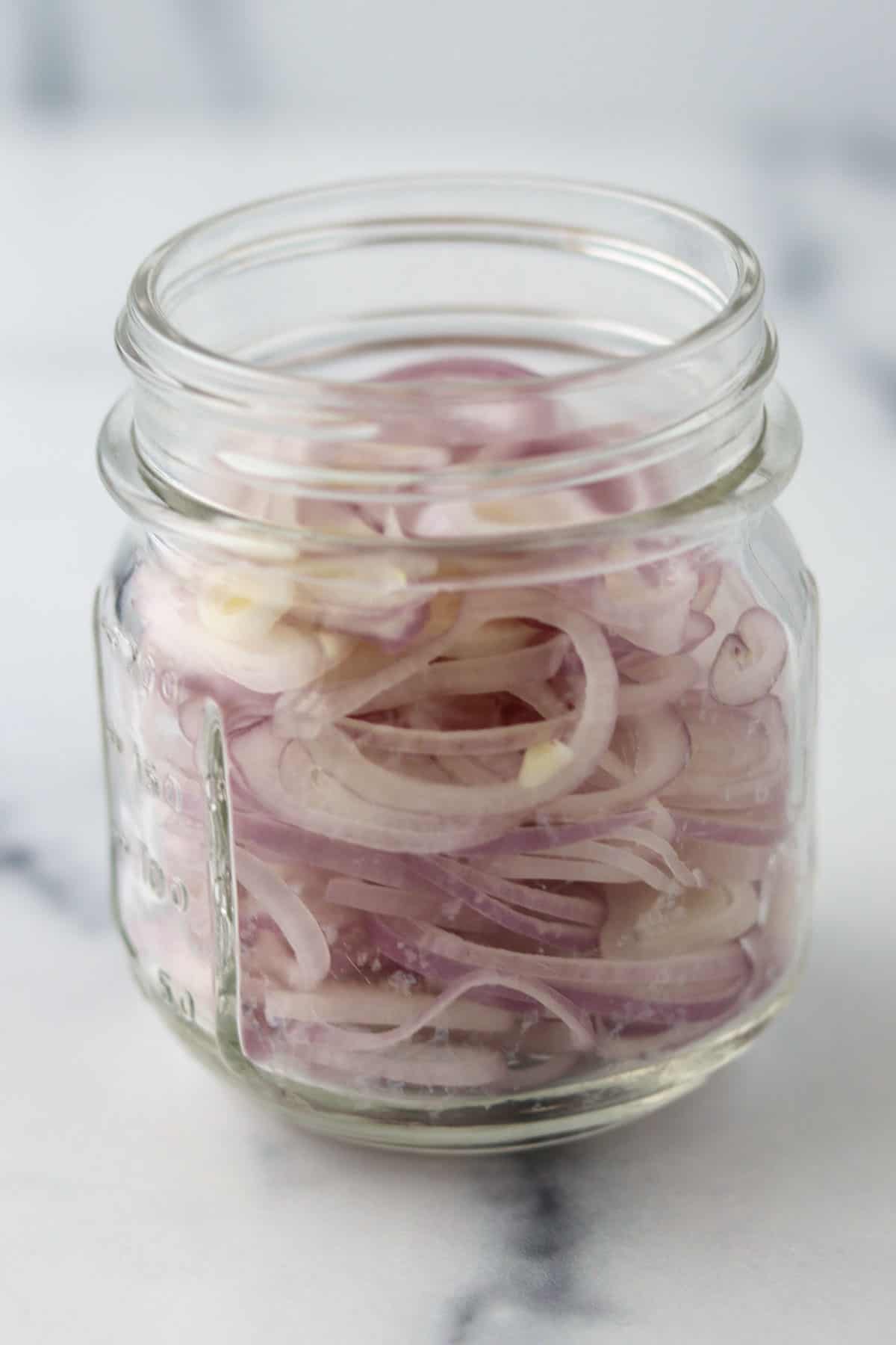 Cut up shallot rings in a glass jar.