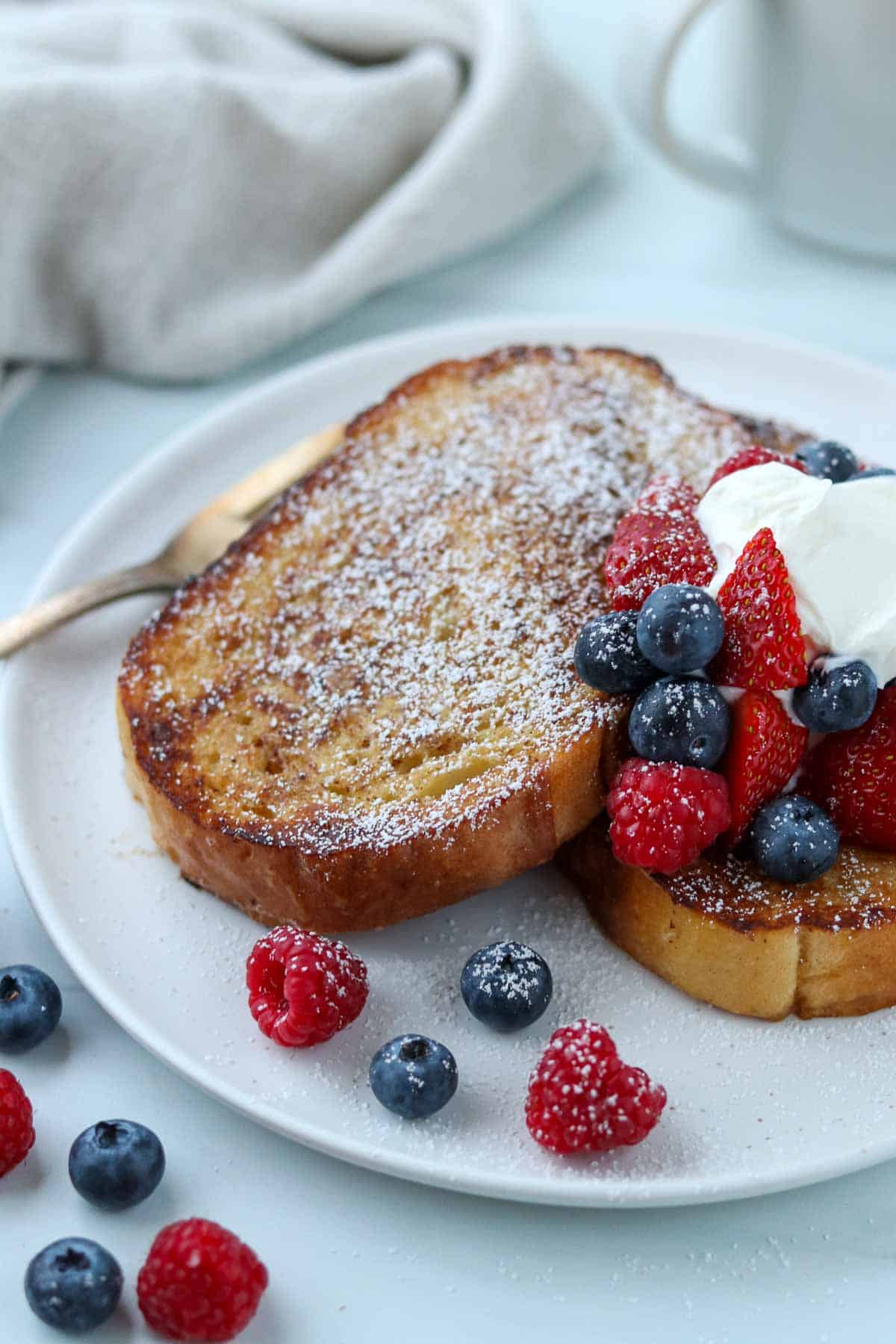 French toast dusted with powdered sugar on a plate with fresh berries.