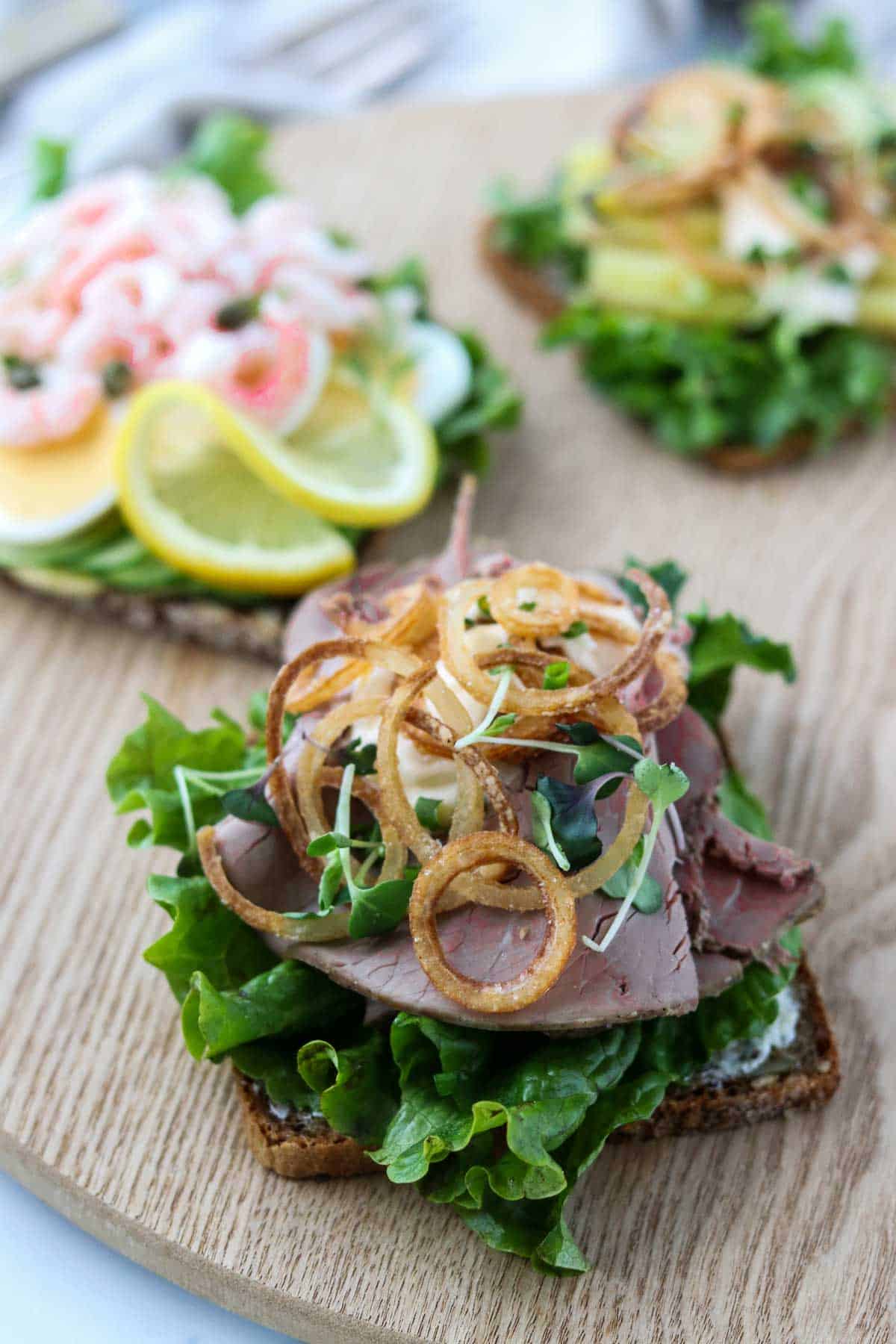 Roast beef smørrebrød on a wooden surface.