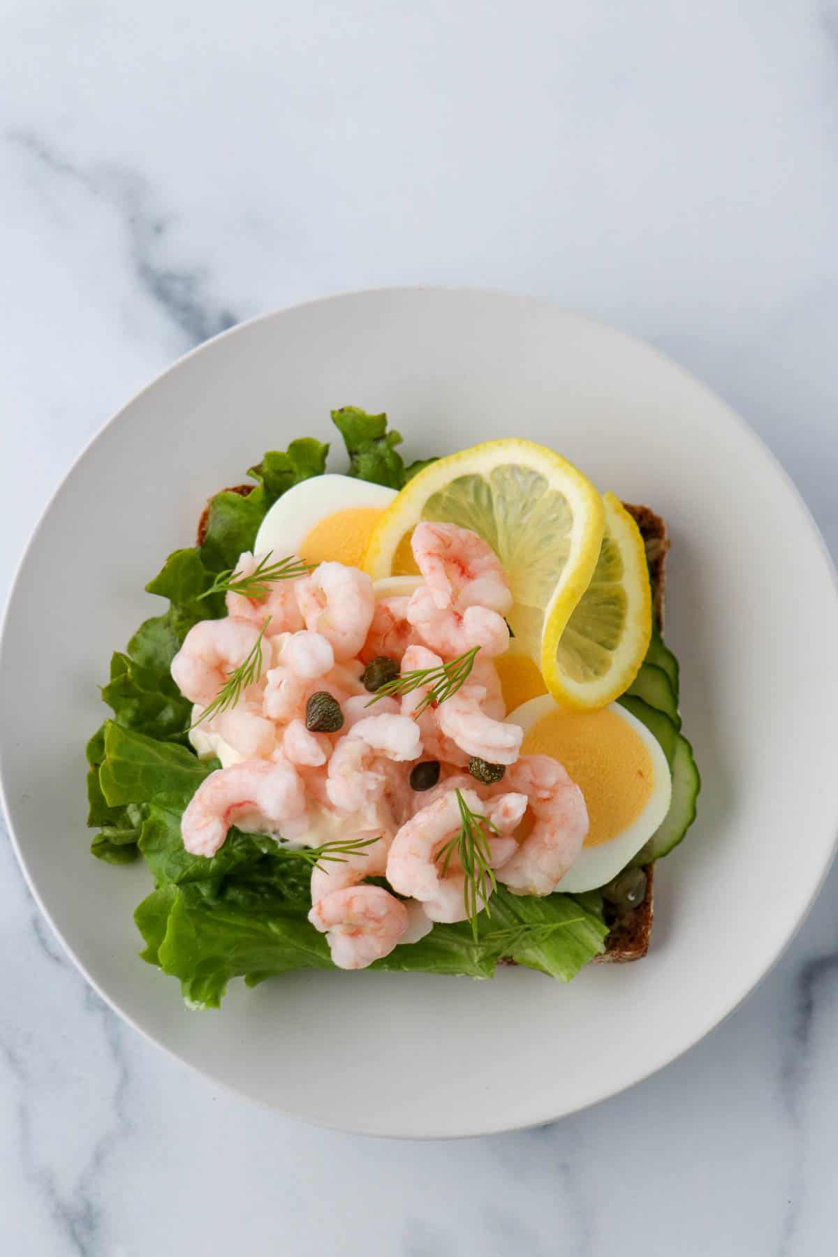 Shrimp smørrebrød with eggs, lemon and lettuce.