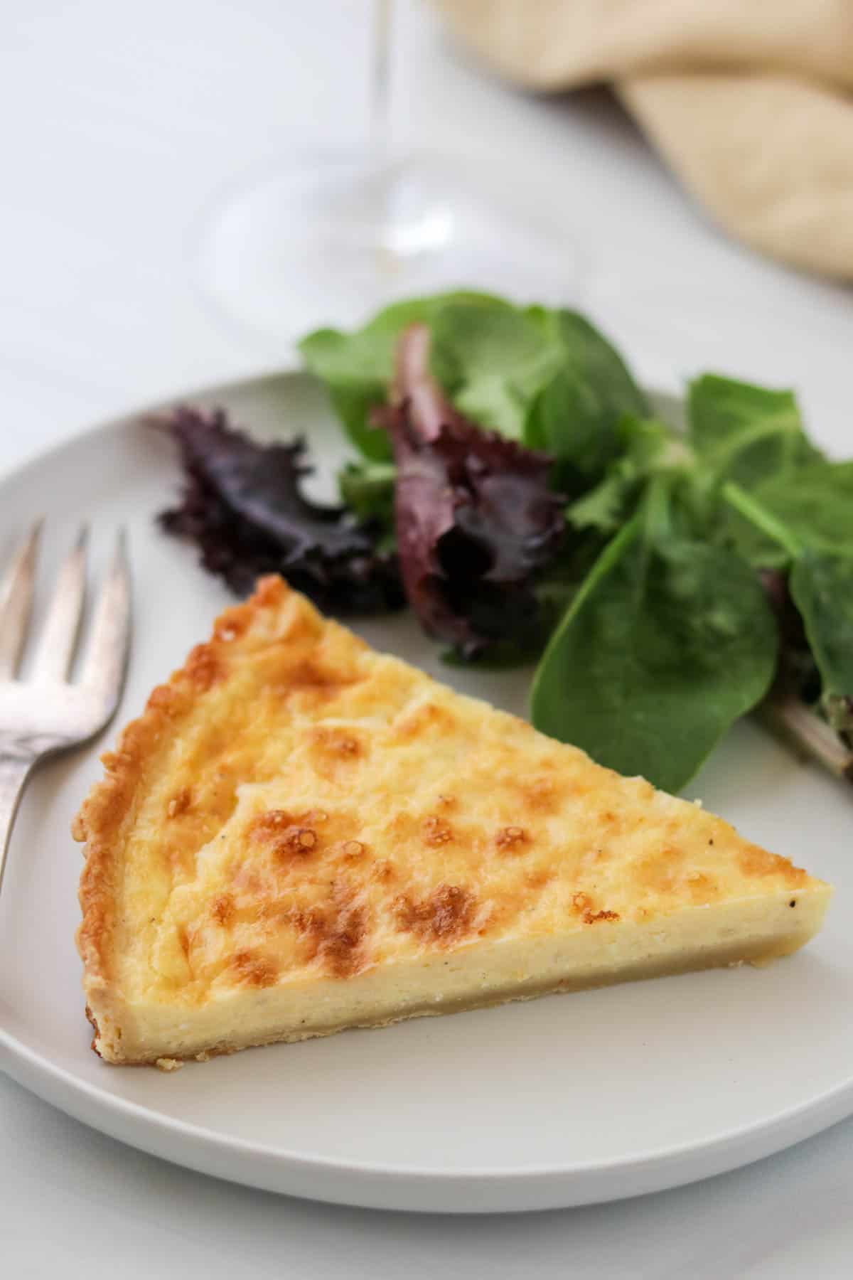 Swedish Cheese Pie (Västerbottenpaj) on a plate with salad and a fork.