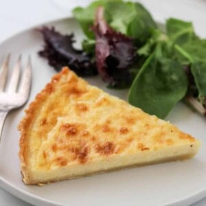 Close up of Swedish Cheese Pie (Västerbottenpaj) with a salad and fork.