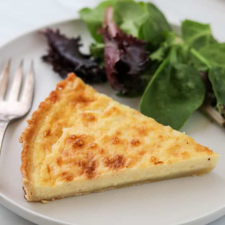 Close up of Swedish Cheese Pie (Västerbottenpaj) with a salad and fork.