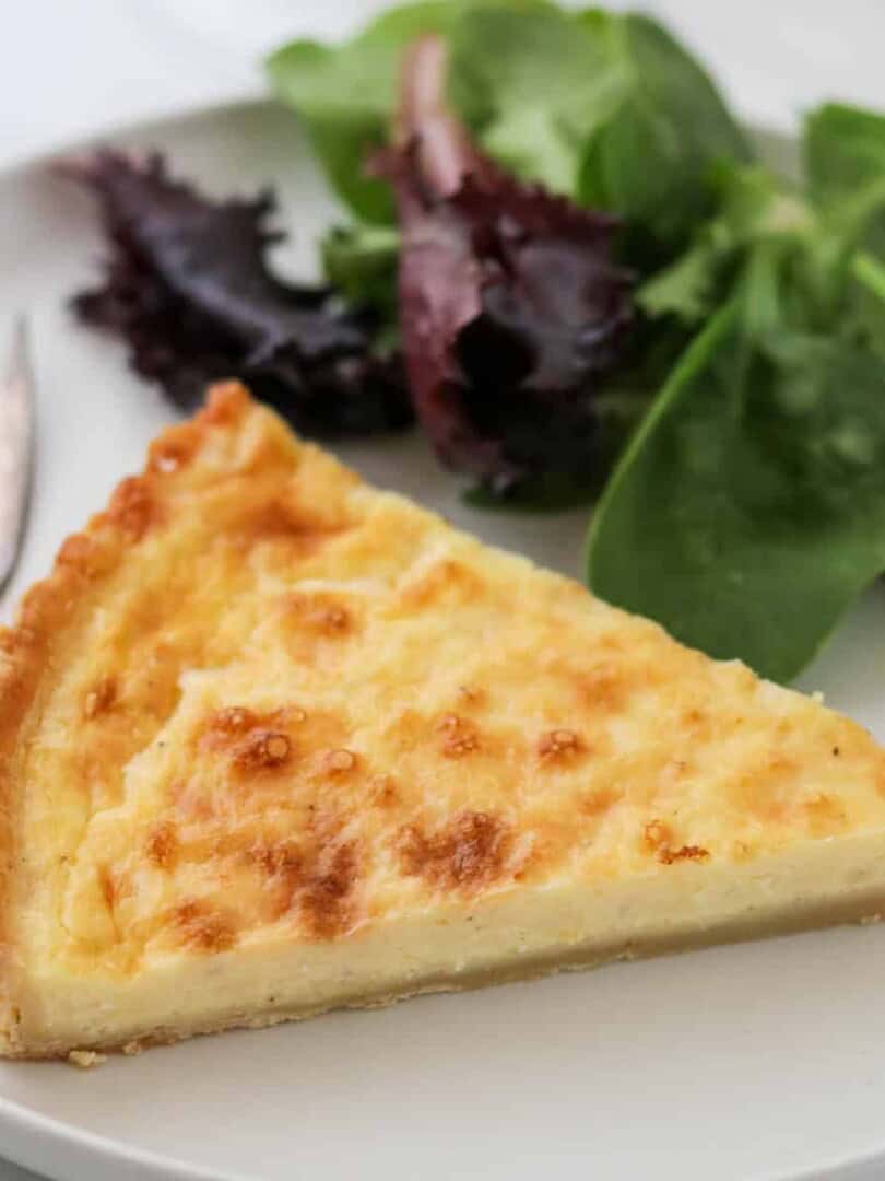 Close up of Swedish Cheese Pie (Västerbottenpaj) with a salad and fork.