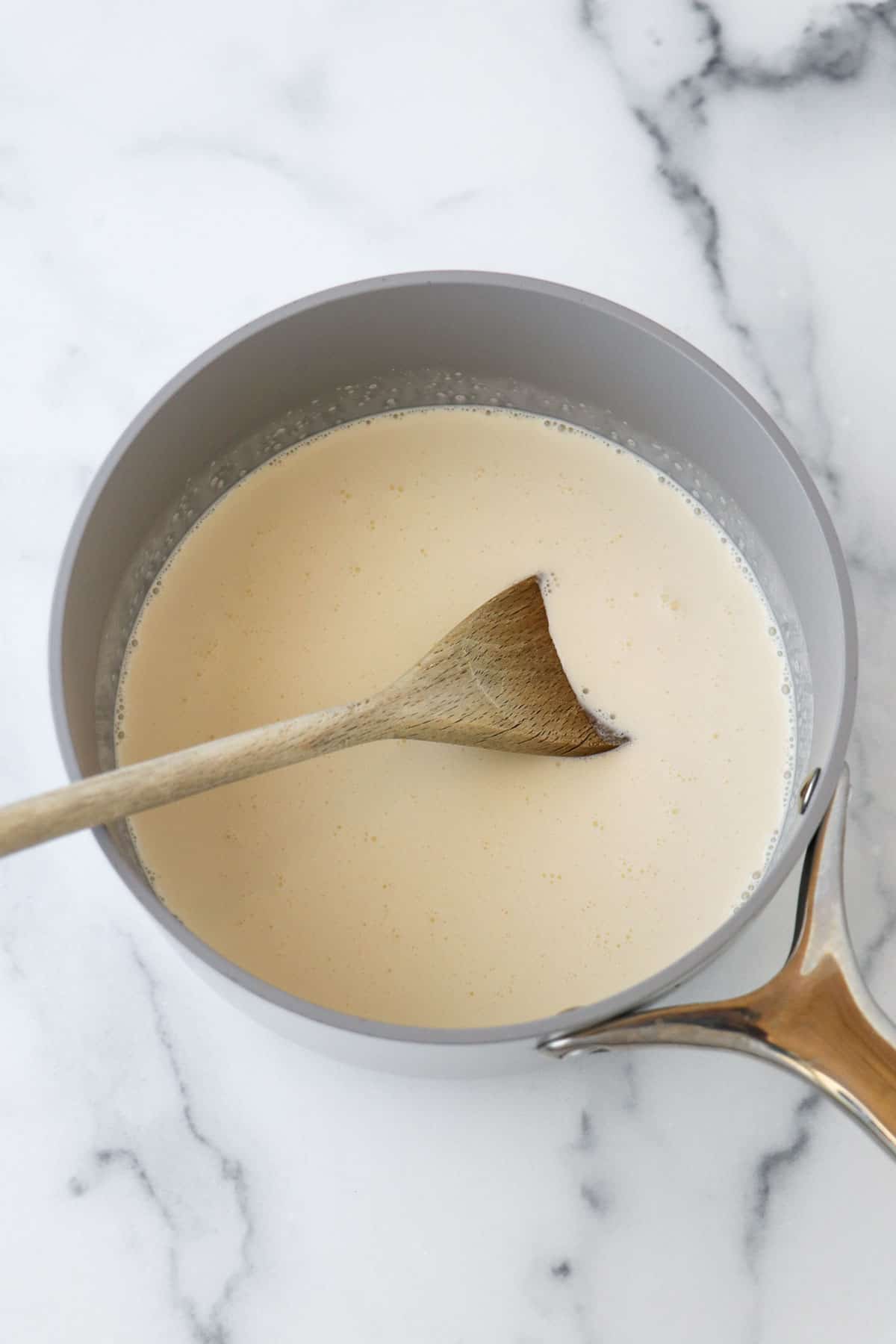 Swedish Cream in a saucepan with a wooden spoon.