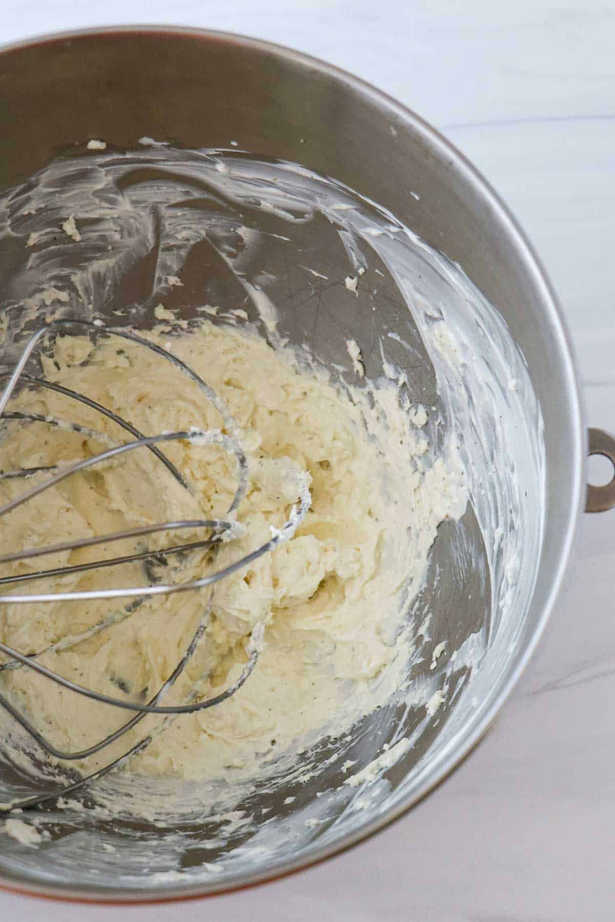 Cream cheese in a mixer bowl with a whisk attachment.